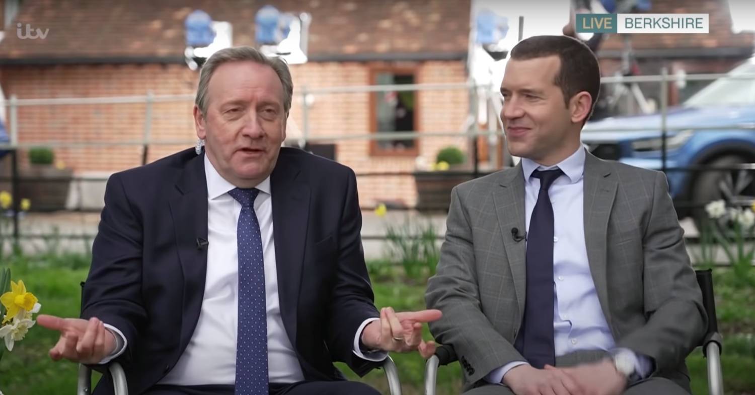 Neil Dudgeon gesticulates on the set of Midsomer Murders alongside another cast member