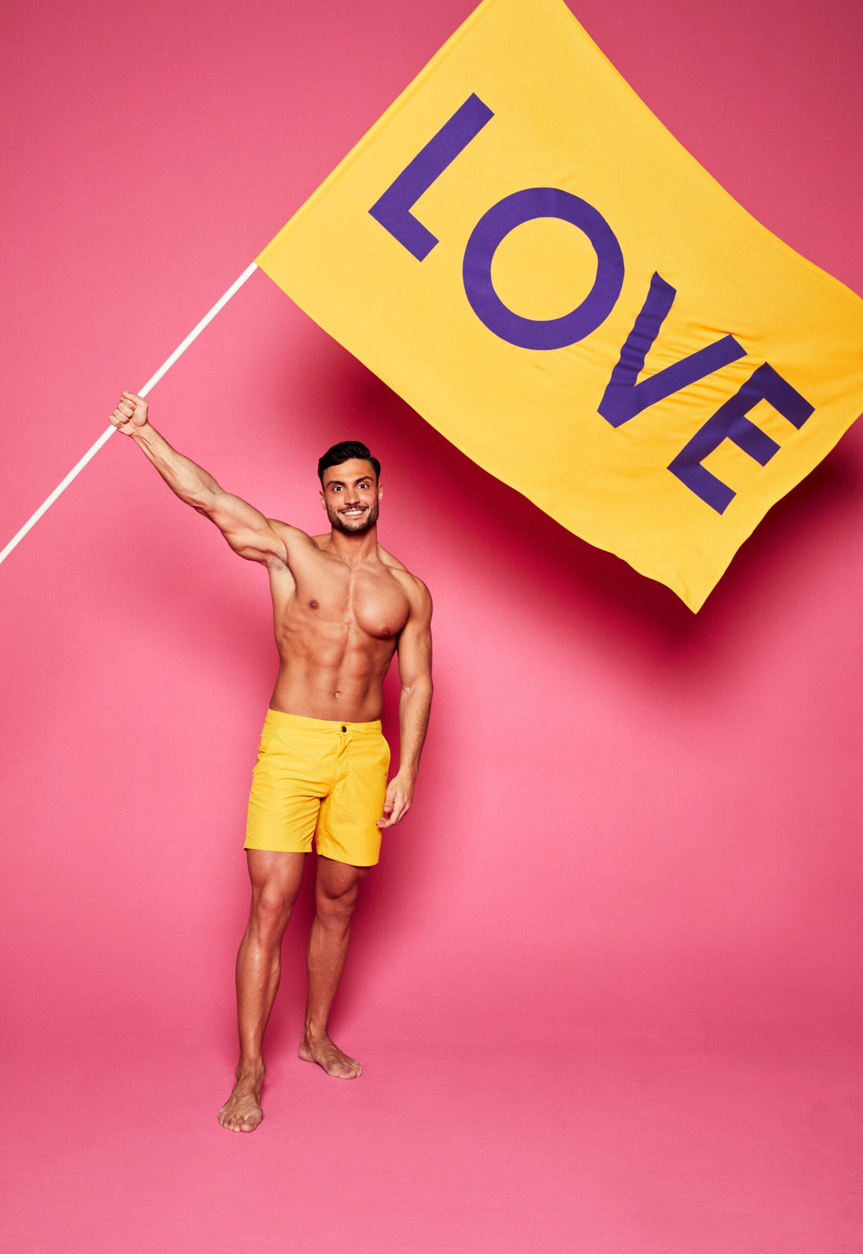 Love Island 2022 star Davide in swim shorts while holding a flag