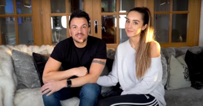 Peter Andre and Emily Andre sitting on a sofa, smiling and talking to the camera