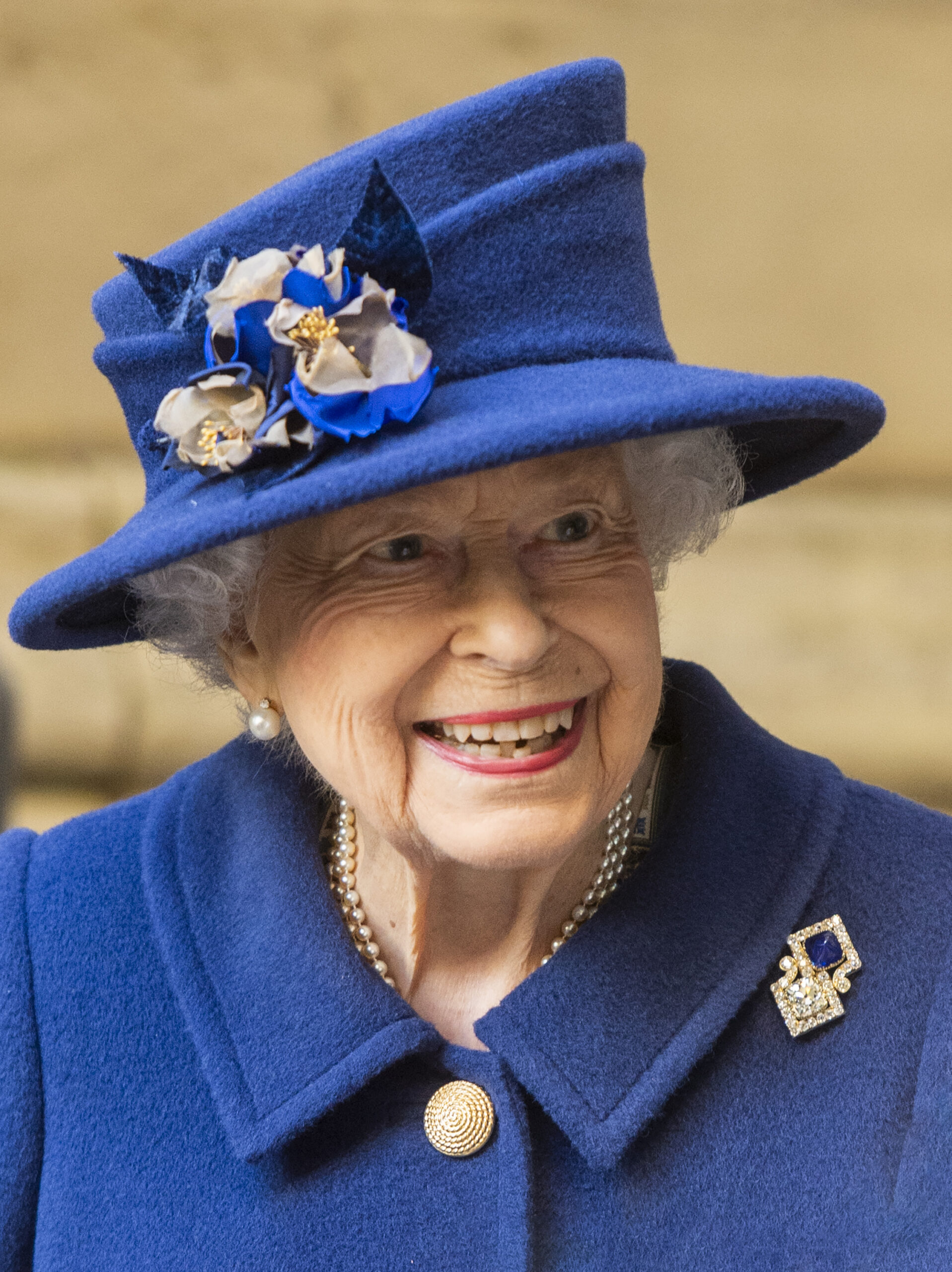 The Queen smiling in all blue outfit during royal engagement