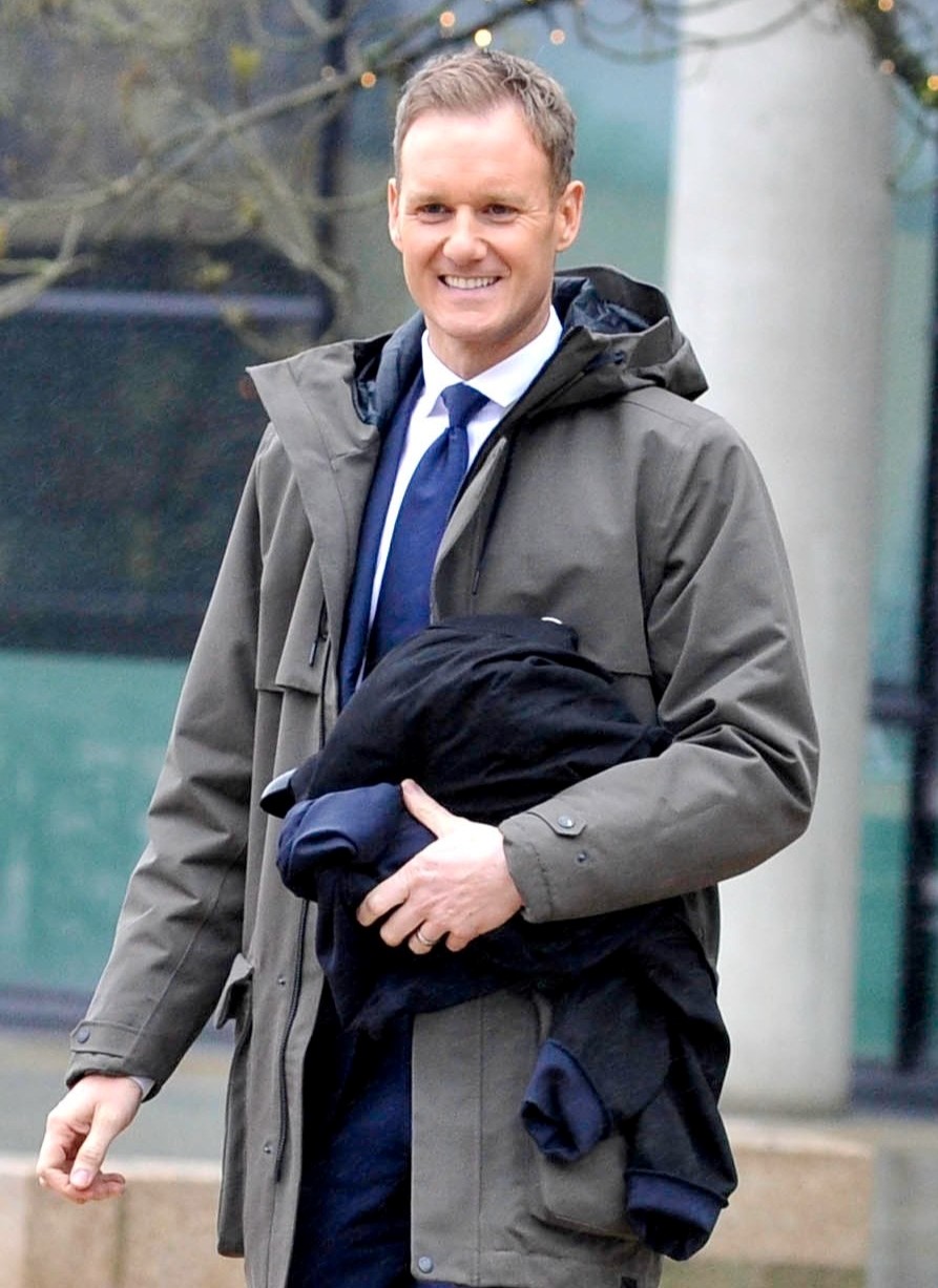 Dan Walker smiles outside BBC studios while holding a coat