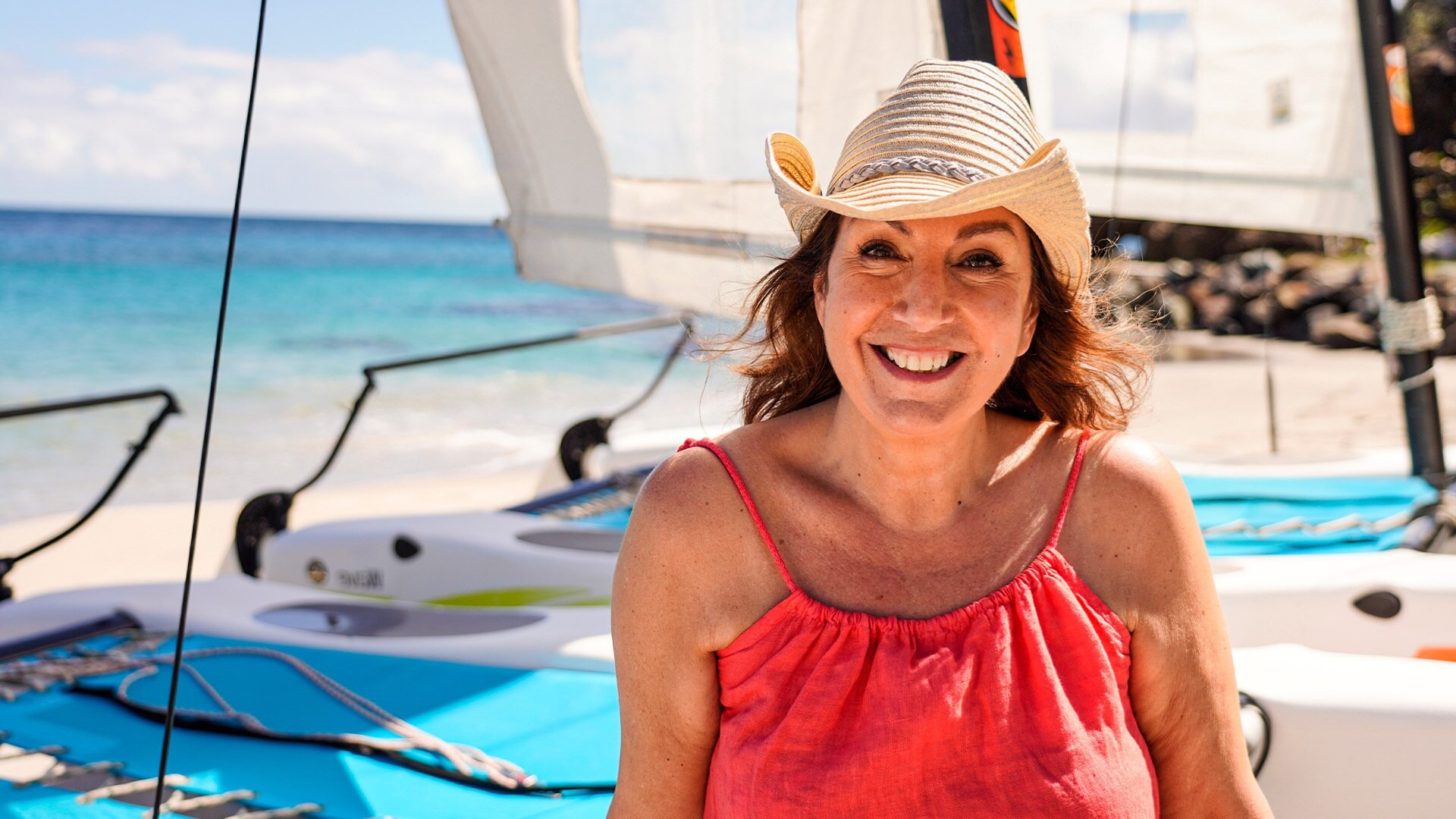 Jane McDonald posing on the beach in a sun hat