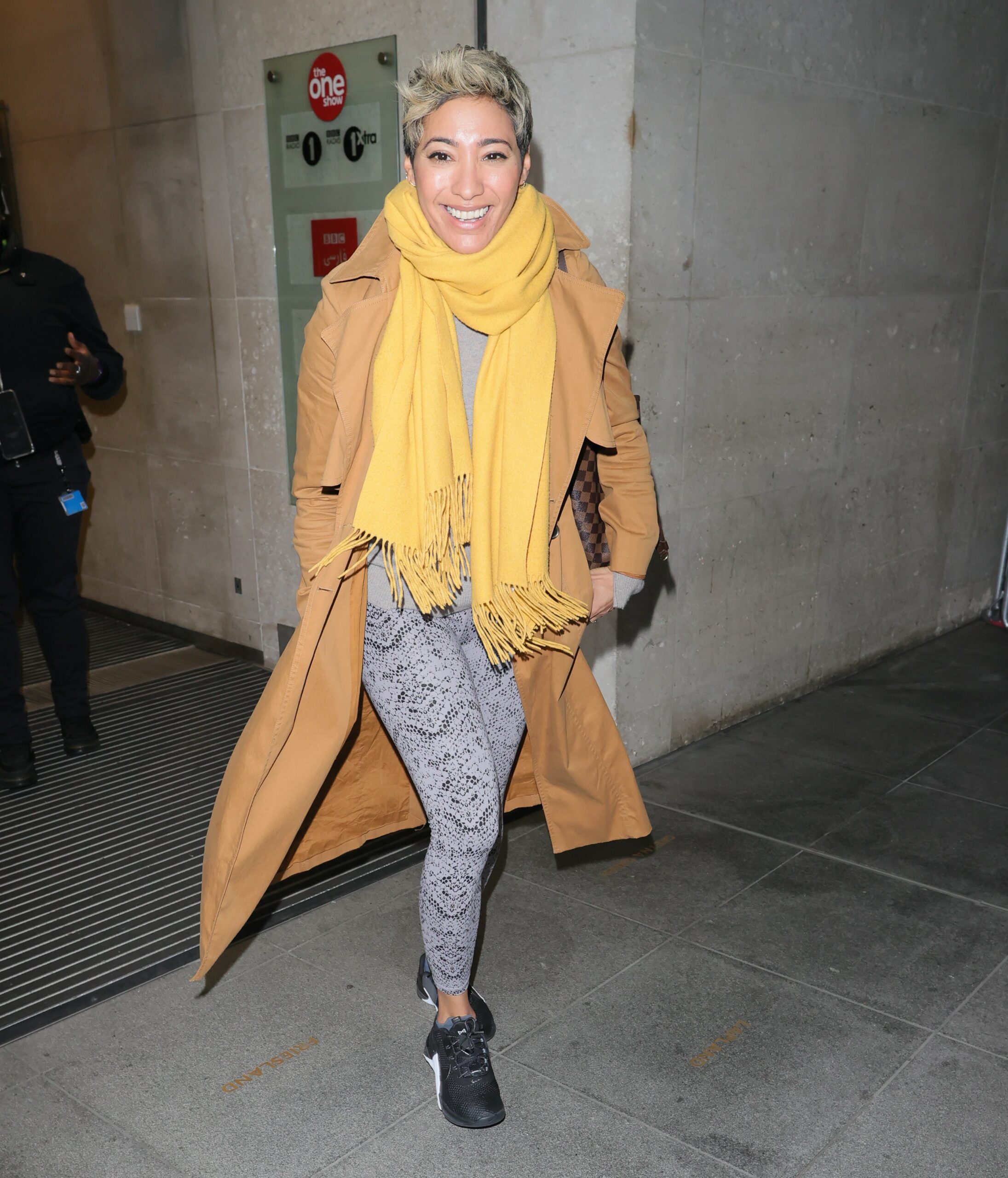 Strictly star Karen Hauer smiling in yellow scarf and orange coat 