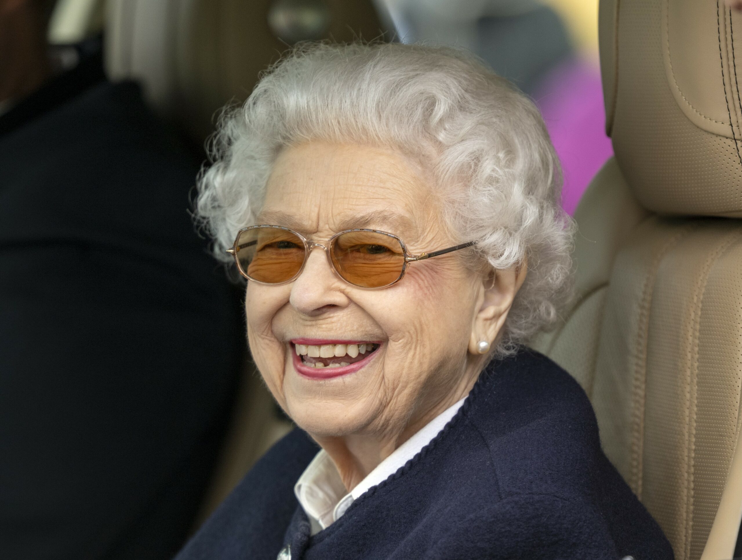 The Queen smiling at cameras in glasses and jumper during royal engagement