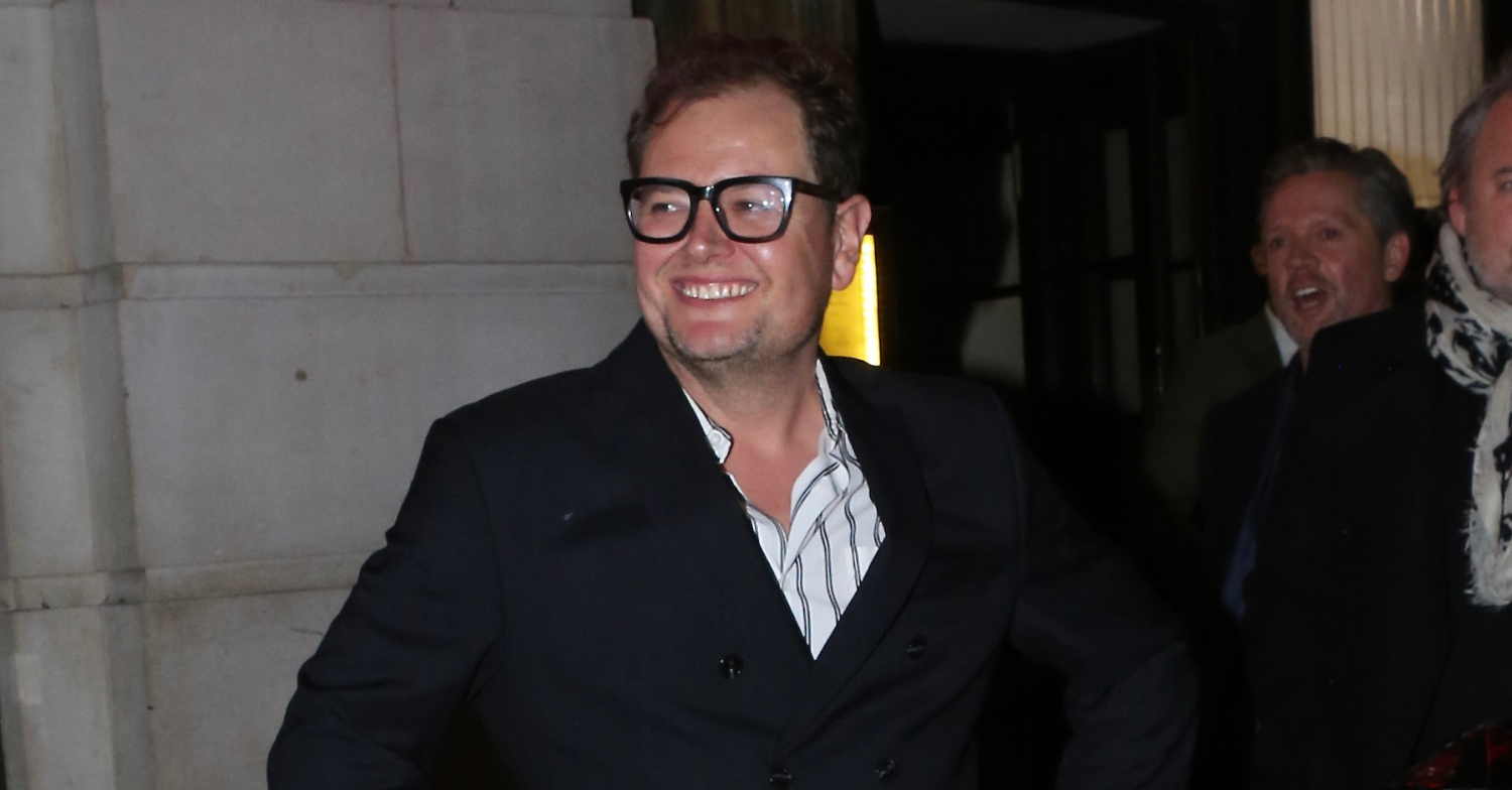 Alan Carr smiling wearing glasses