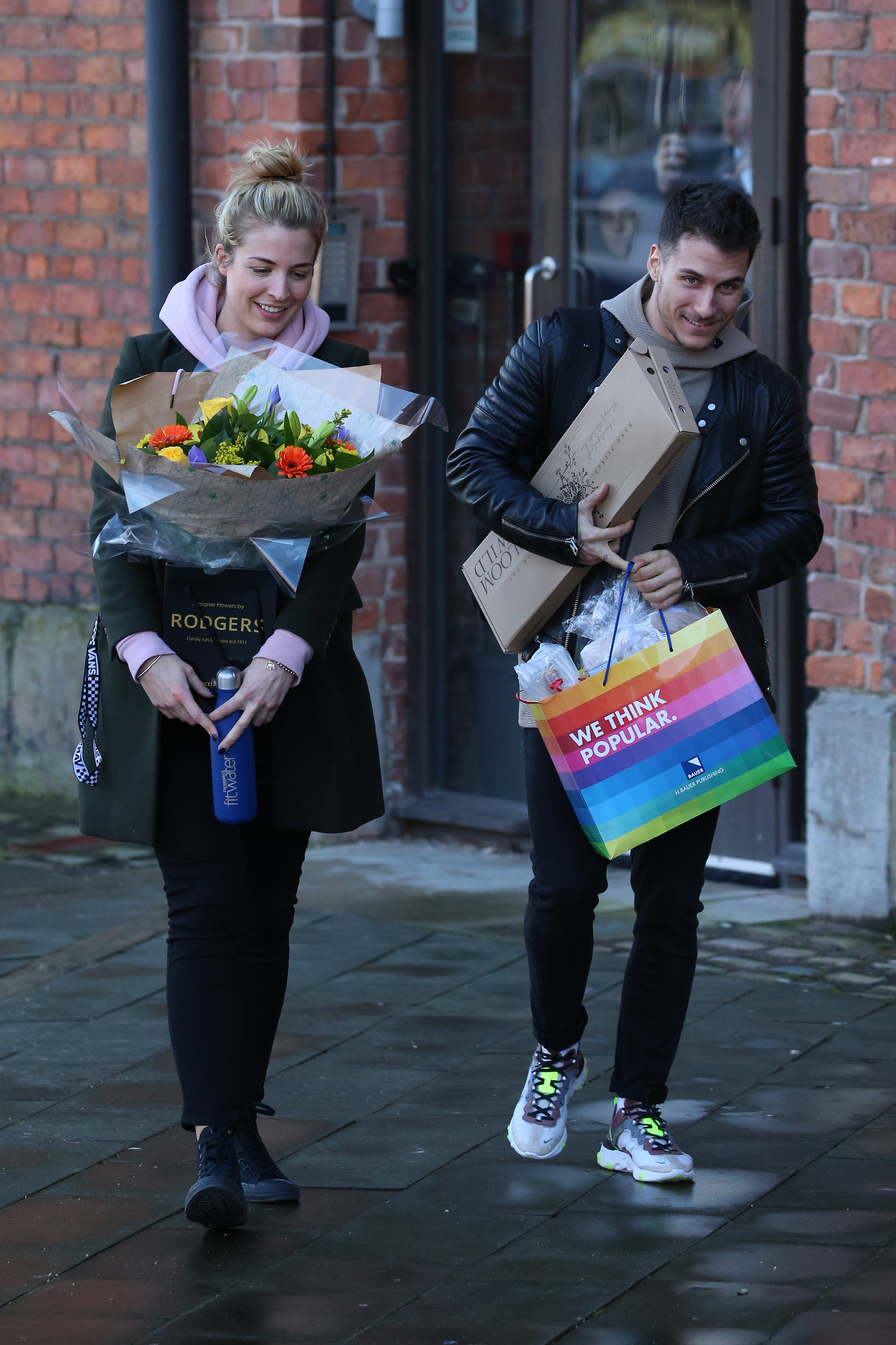 Gemma Atkinson and Gorka Marquez carrying bags and flowers