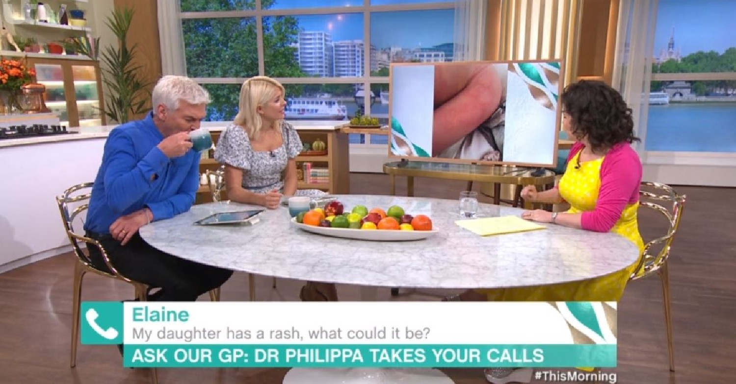 Phillip Schofield drinking a cup of tea as Holly Willoughby and Dr. Phillipa Kaye look at a picture of a rash on a screen on This Morning today
