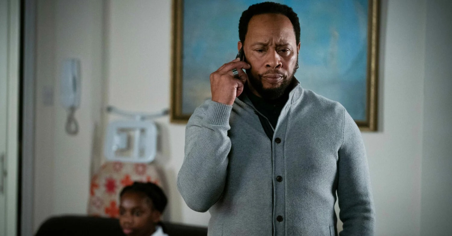 Mitch Baker on the phone, looking concerned in EastEnders