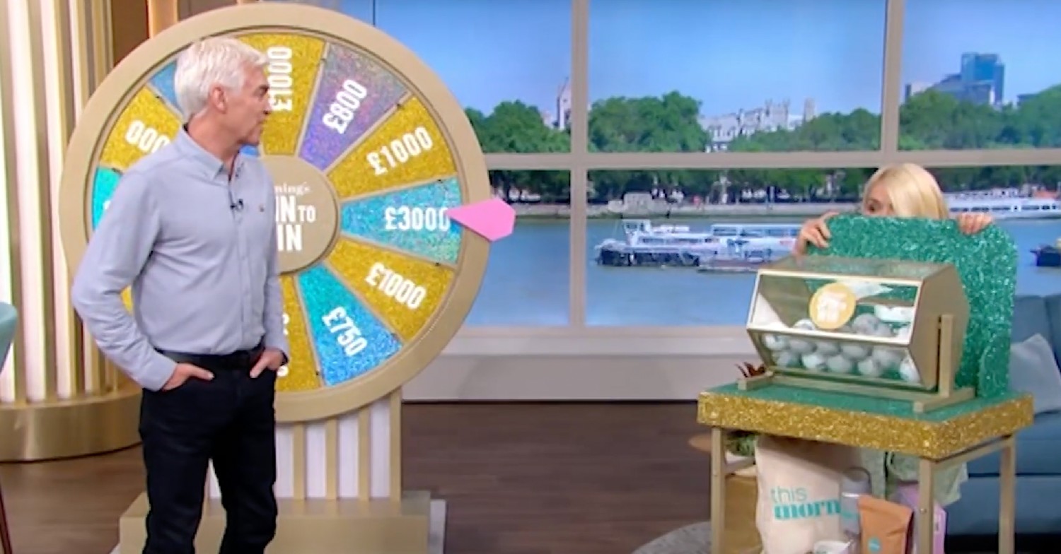 Phillip Schofield looking at Holly Willoughby as she hides behind the tombola on This Morning today