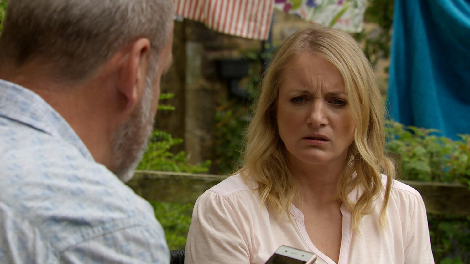 Emmerdale Jimmy looks at his phone as confused Nicola watches on