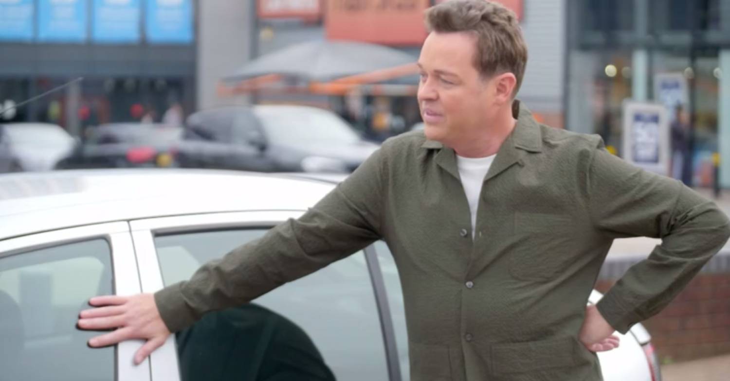 Stephen Mulhern rests his hand on a car