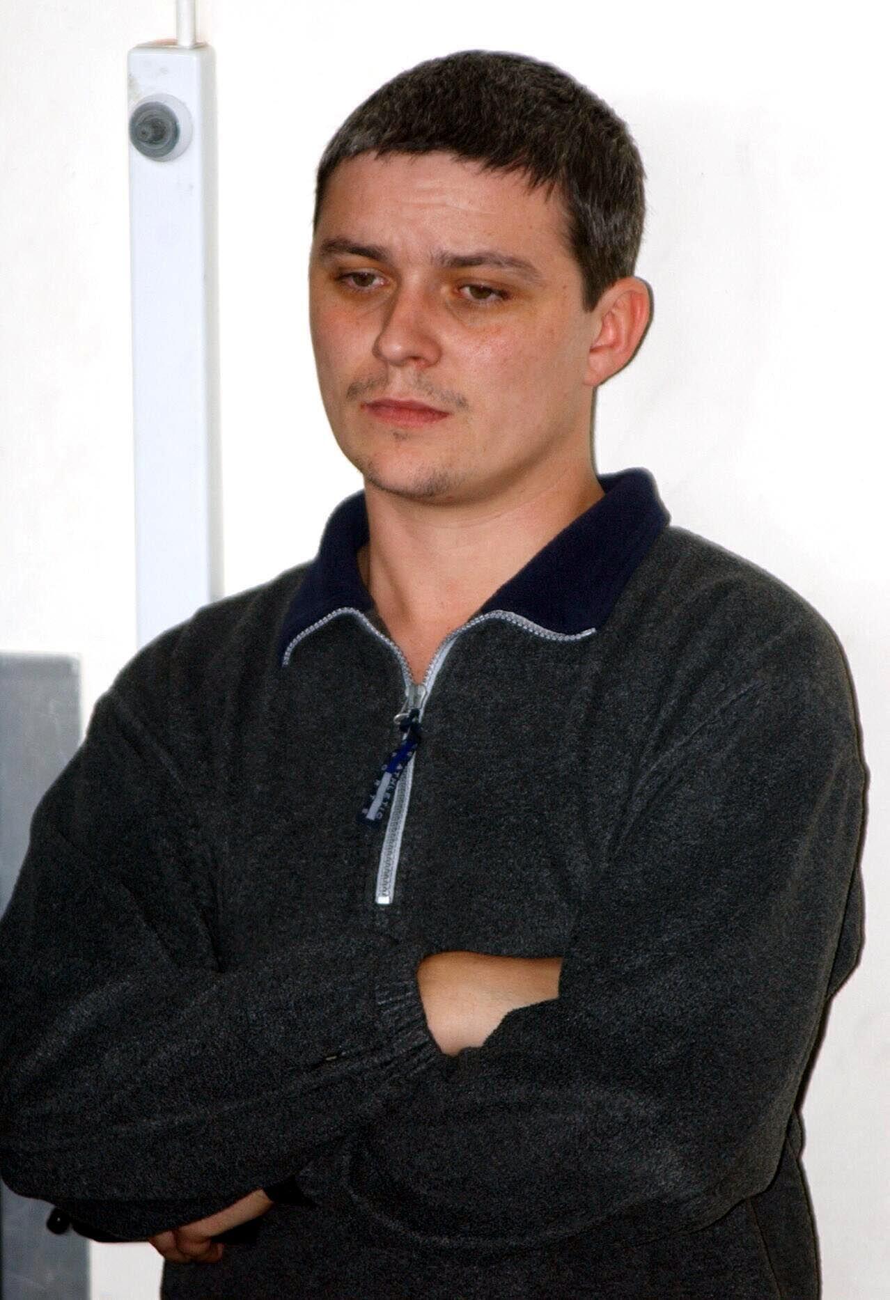 Ian Huntley stares into the distance, with his arms crossed