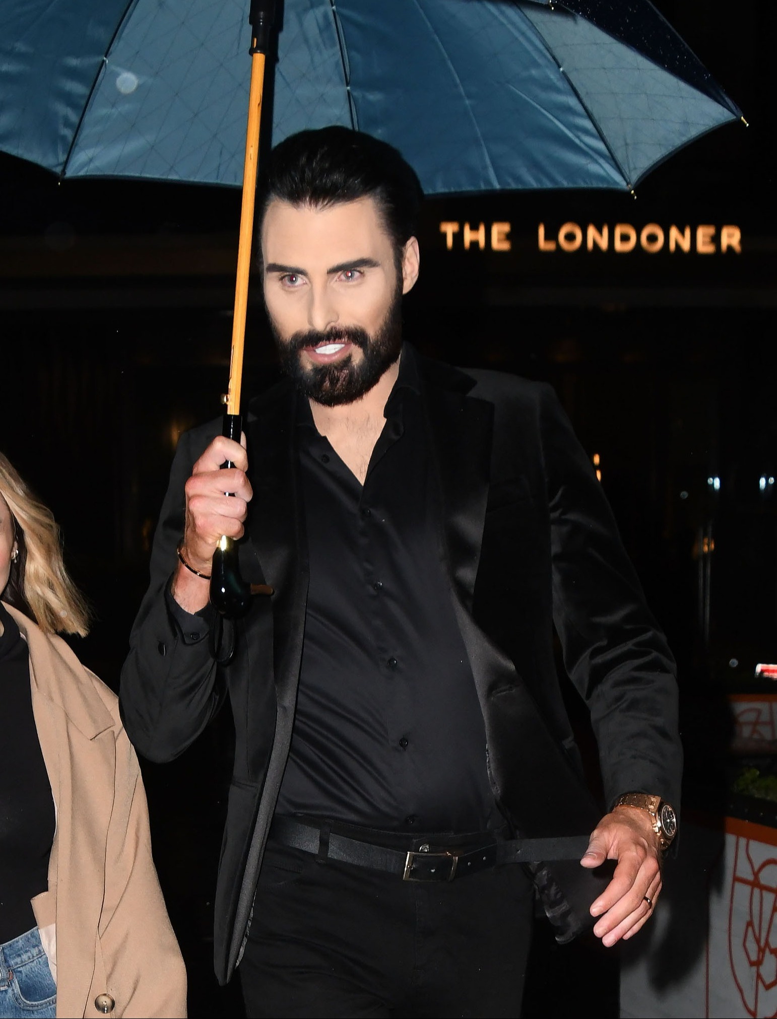 Rylan Clark smiles and holds umbrella outside The Londonder Hotel