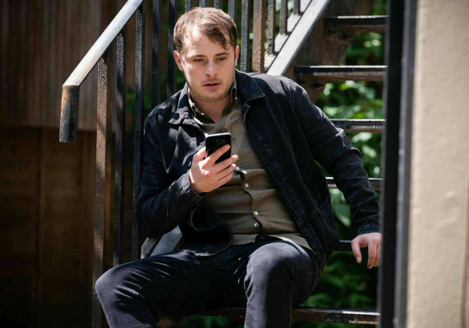 Disheveled Ben Mitchell holds his phone on the stairs of the Albert