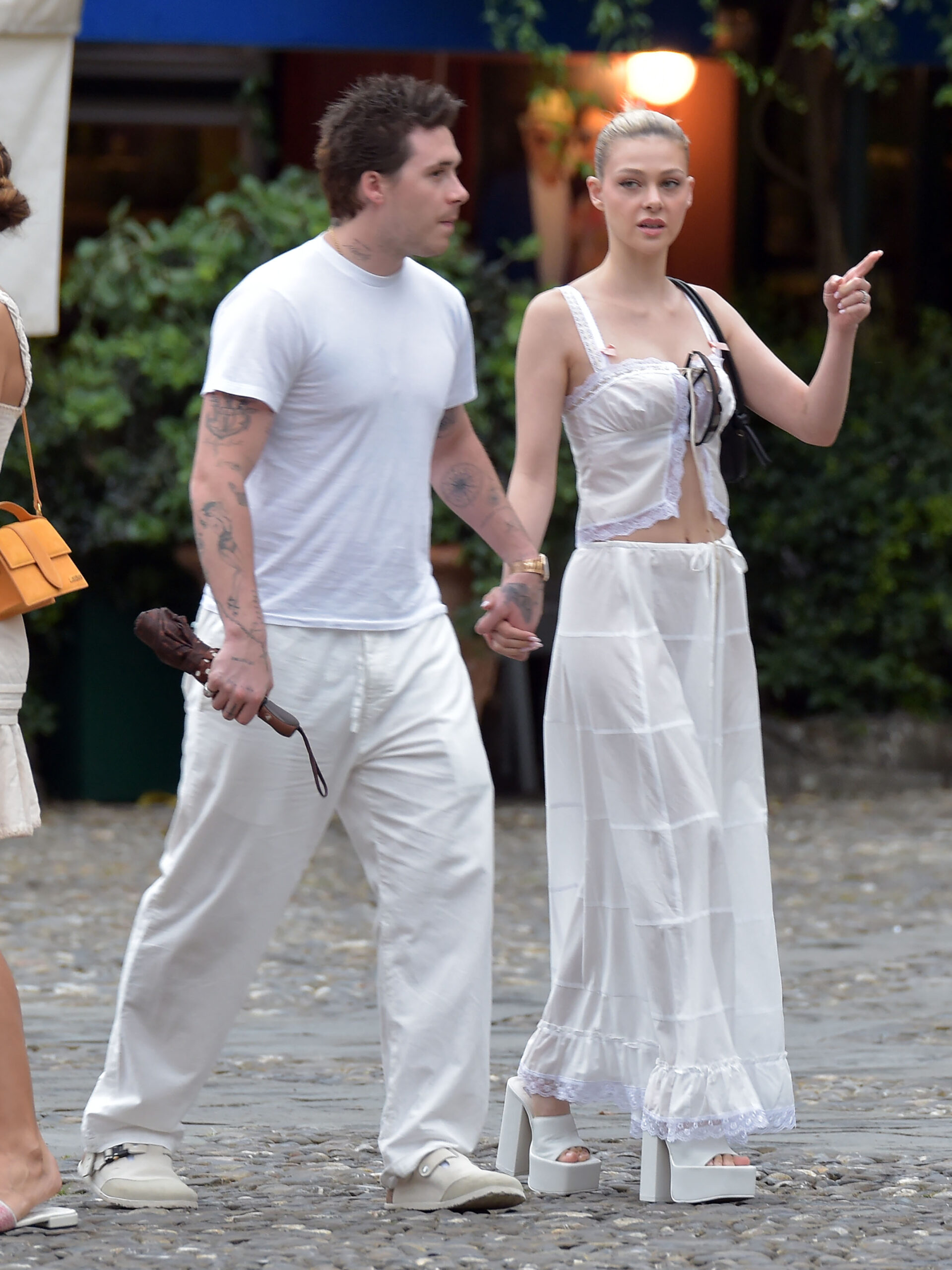 Nicola Peltz and Brooklyn Beckham walk arm in arm.
