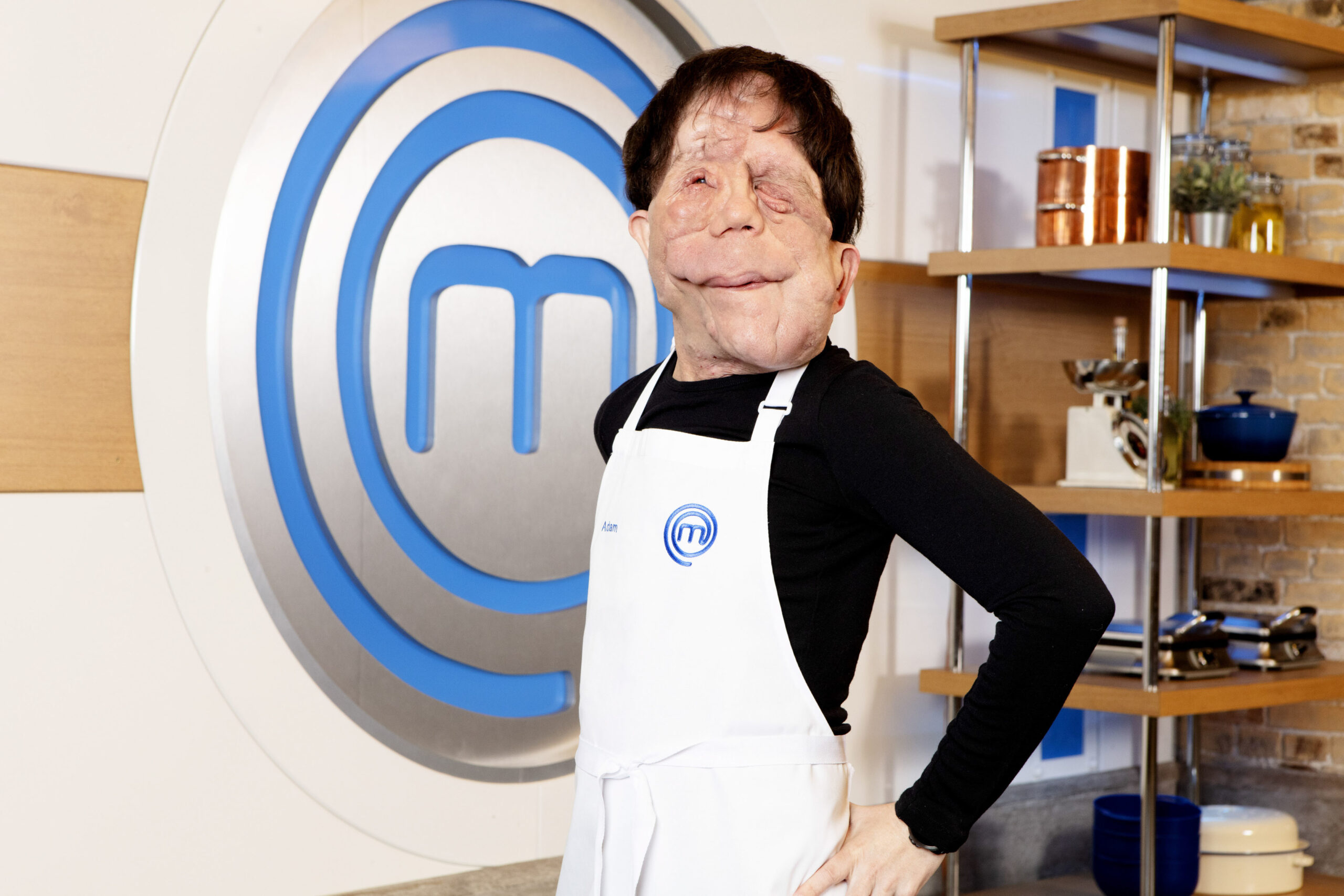 Adam Pearson poses alongside the Masterchef background with his apron on