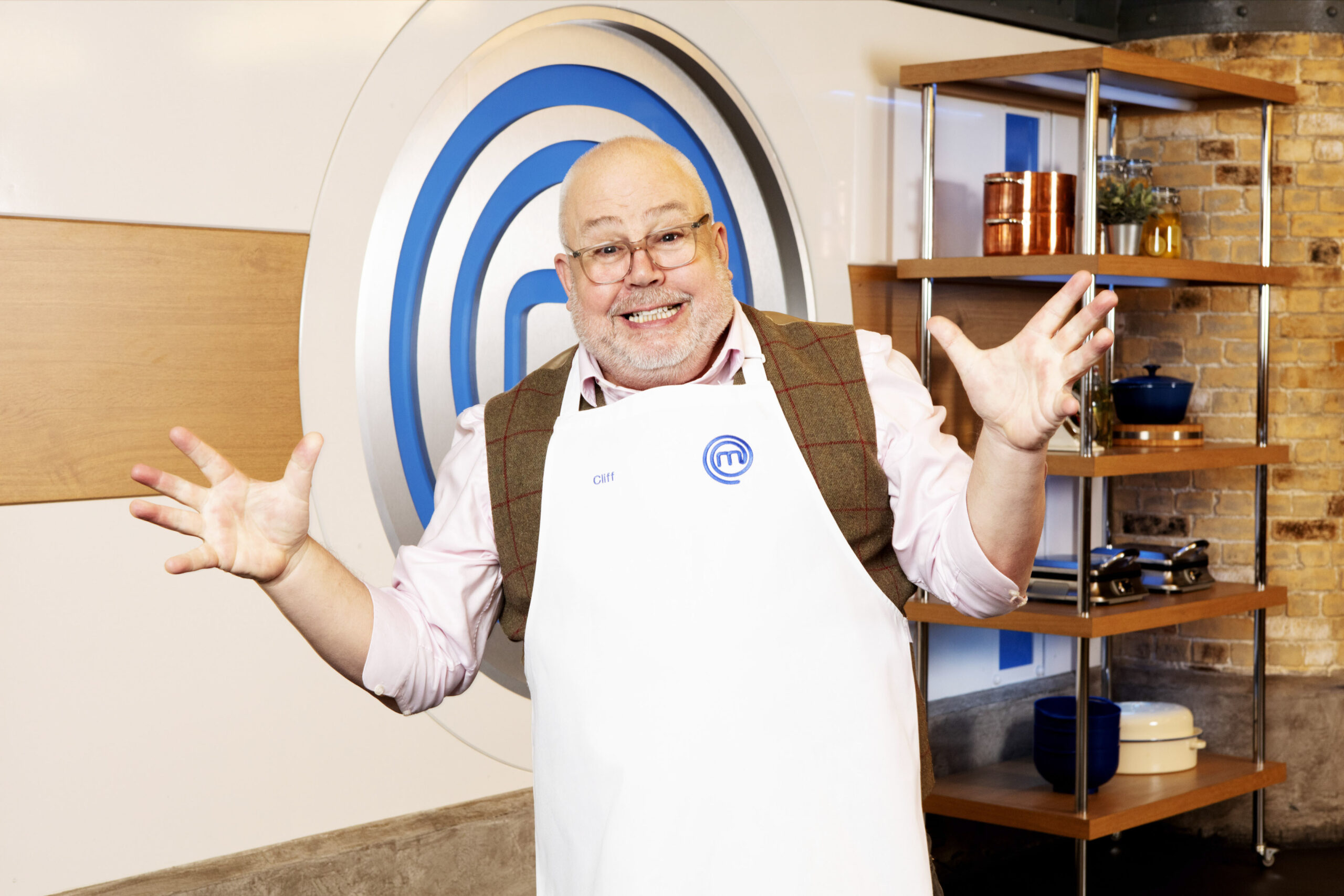Cliff Parisi poses with a smile and hands raised in his Masterchef Apron