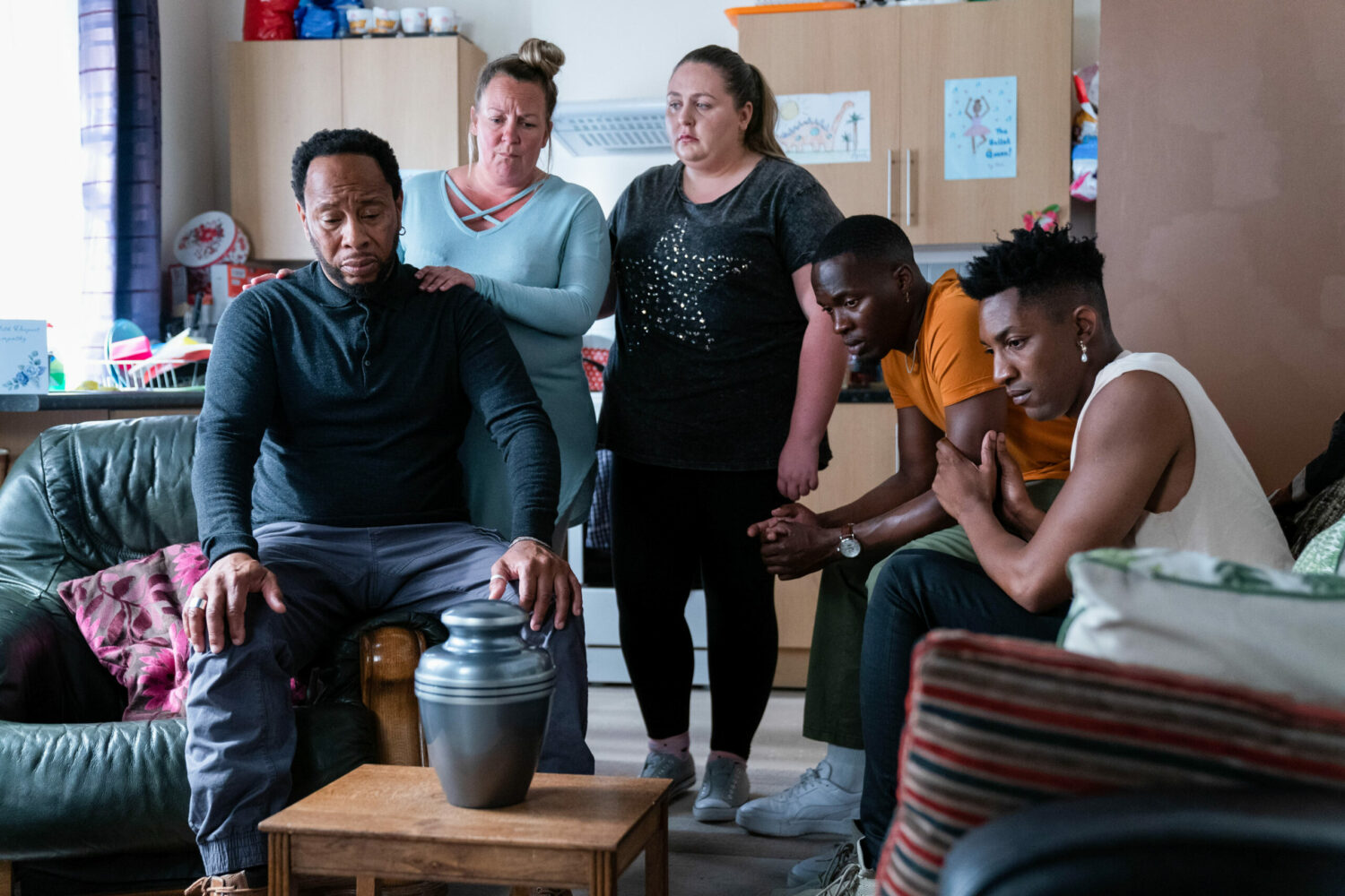 The Bakers/Taylors gather around Avery's urn in EastEnders