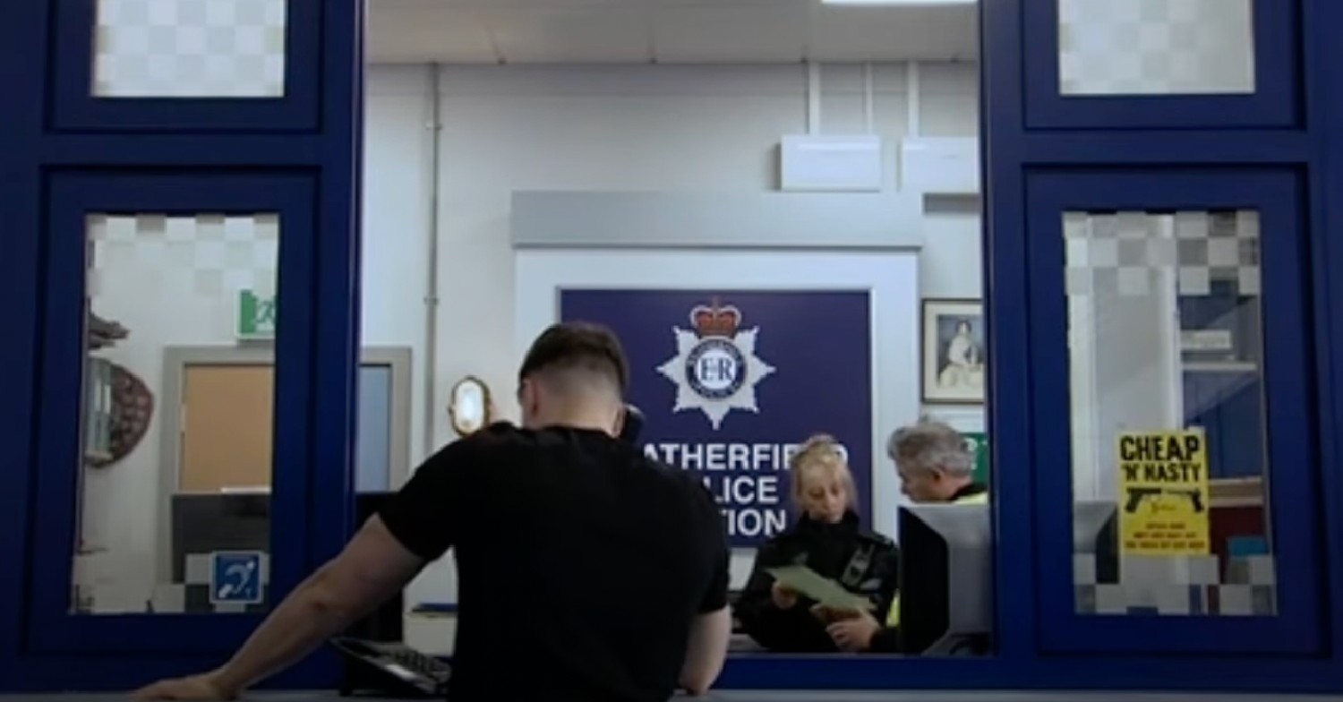 Ryan Connor facing away from camera police station phone