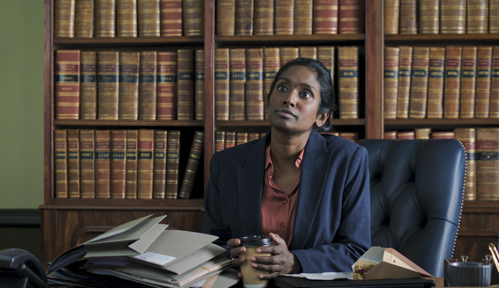 Shetland,10-08-2022,Generic Portraits,Maggie Kean (ANNEIKA ROSE) She sits at a desk with books behind her with a stoic face