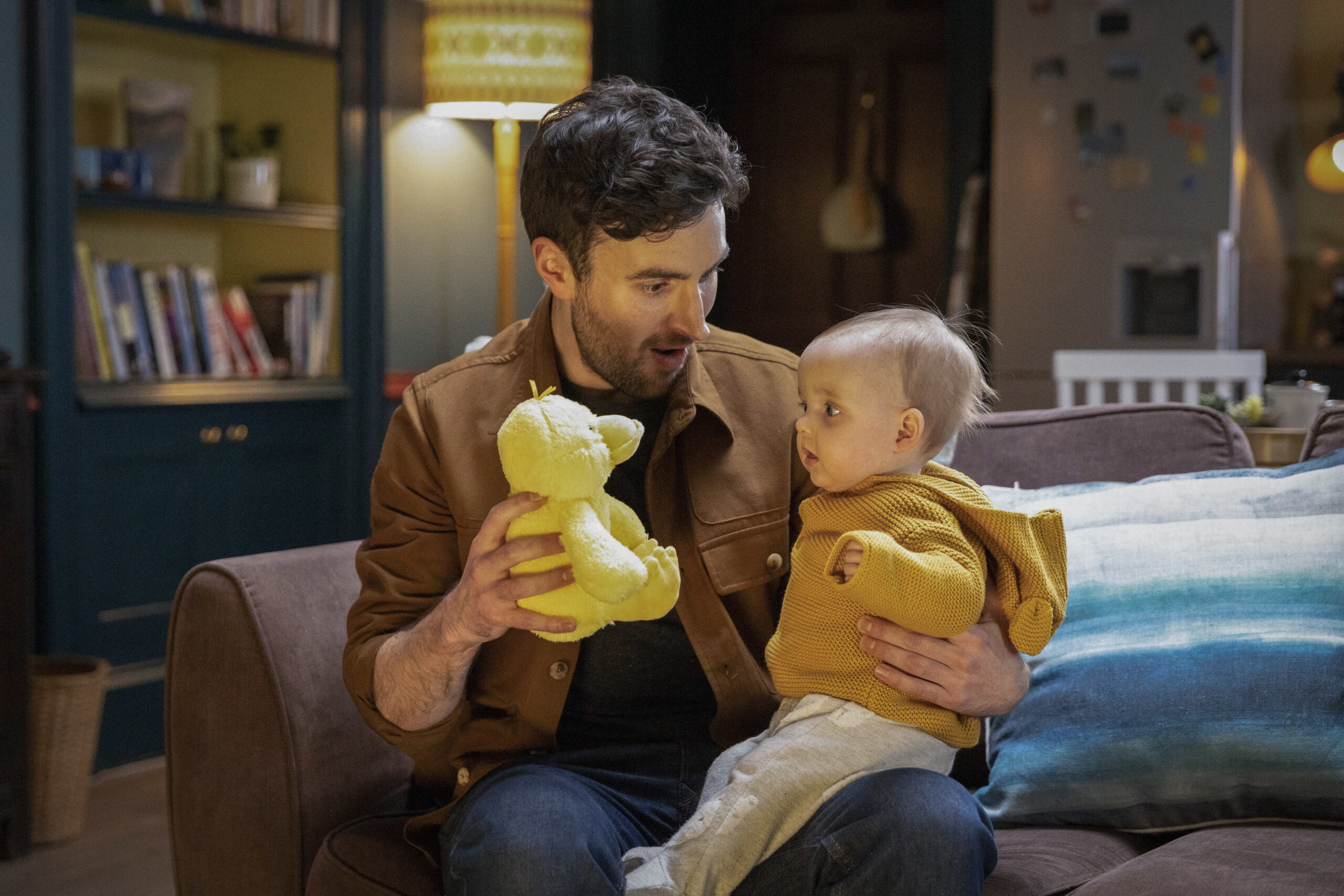 Shetland,14-09-2022,6,Donnie (ANGUS MILLER) He sits with his and Tosh's baby playing with a large rubber ducky and smiling 