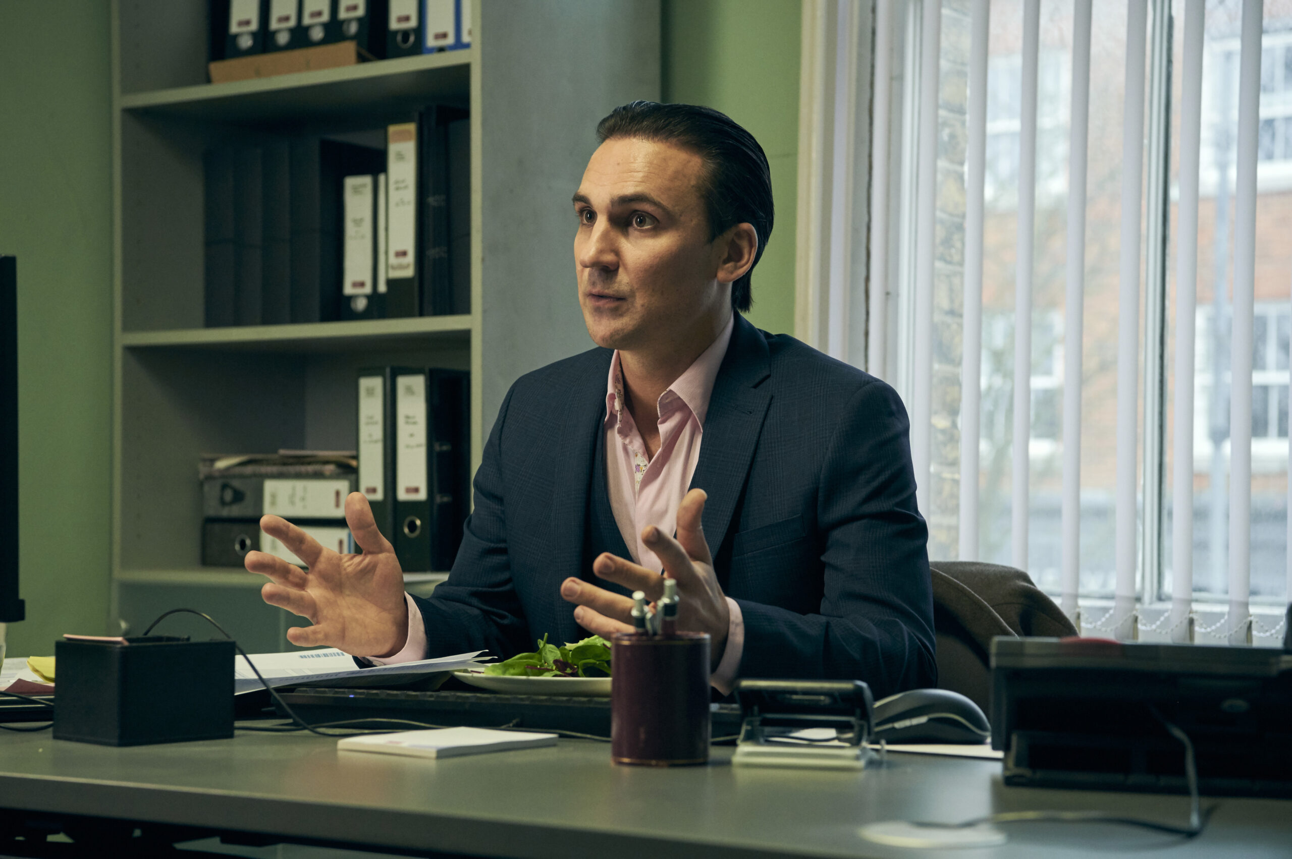 Henry Lloyd-Huges as Jamie, he sits in an office with his hands raised in Marriage on BBC One