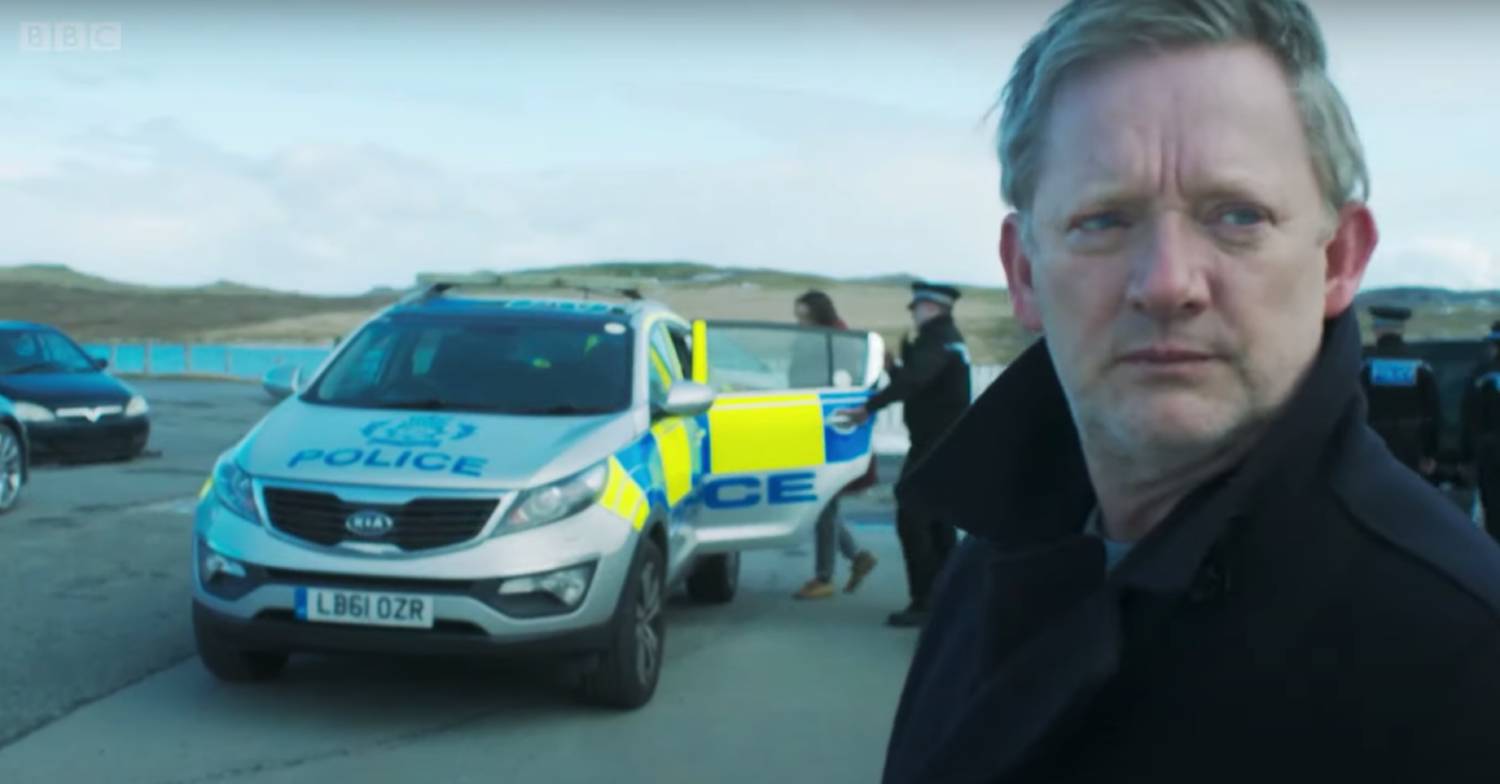 Douglas Henshall as Jimmy Perez in Shetland near to a police car