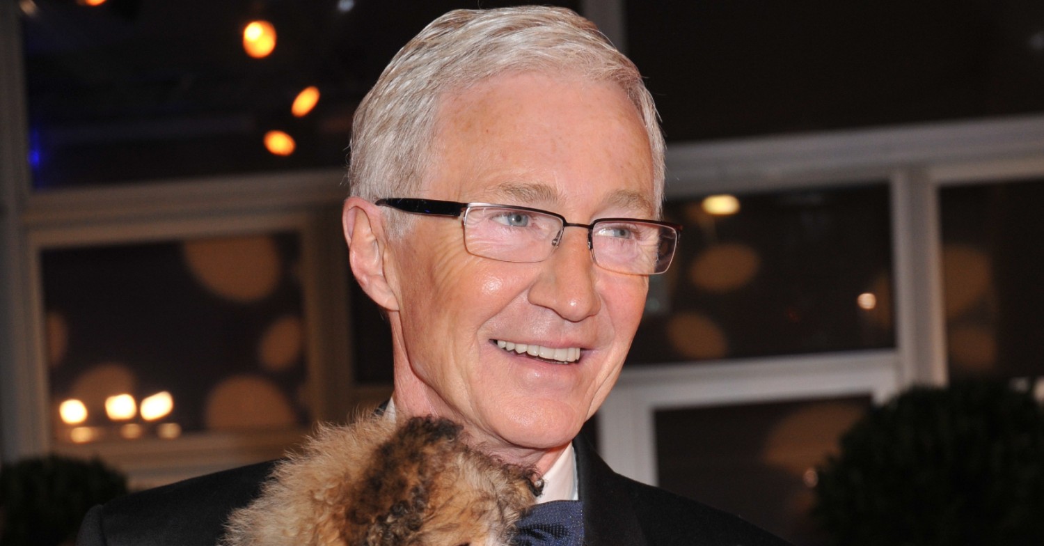Paul O'Grady smiles for camera while holding dog.