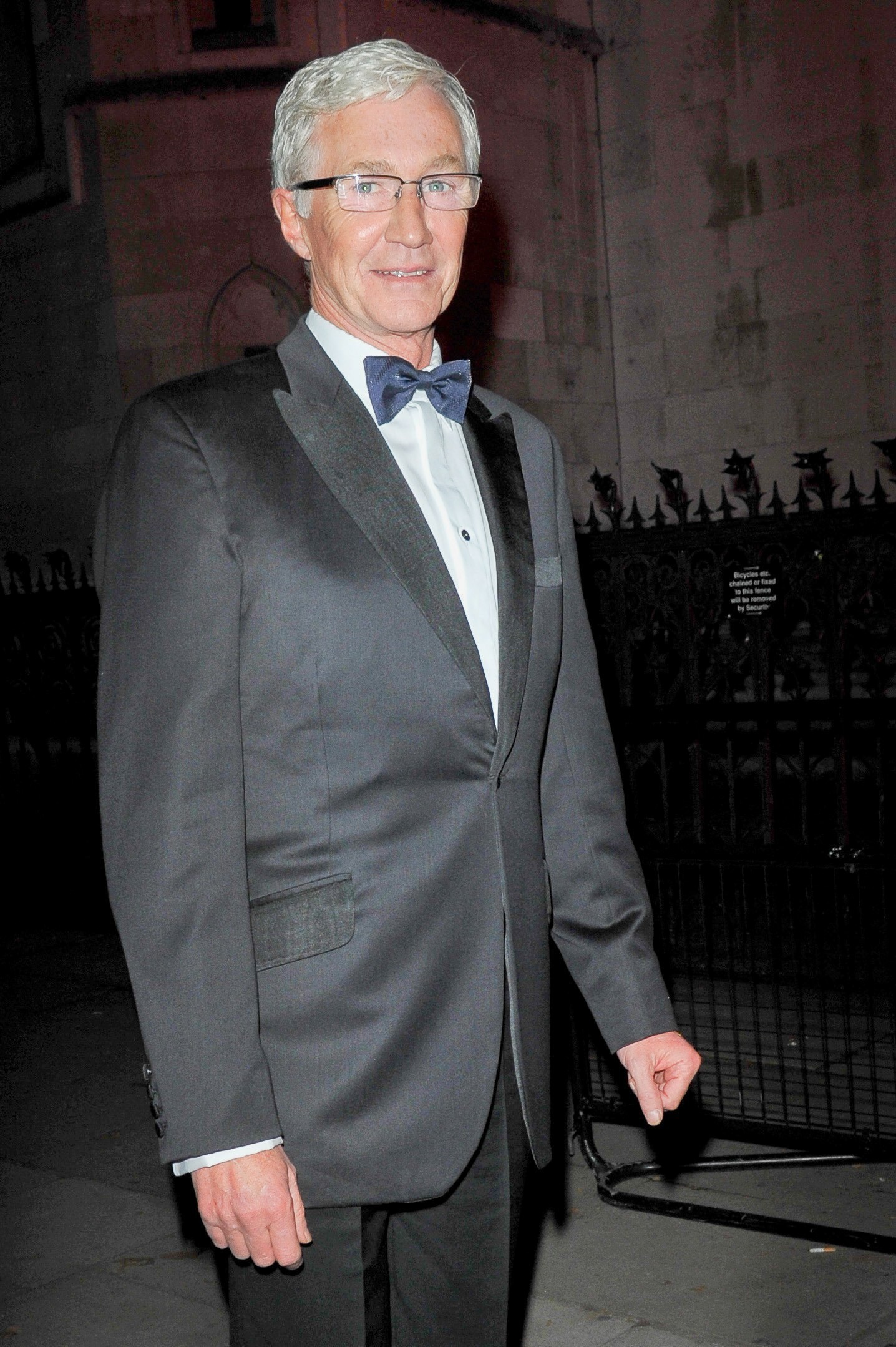 Paul O'Grady smiles in a suit and bow tie