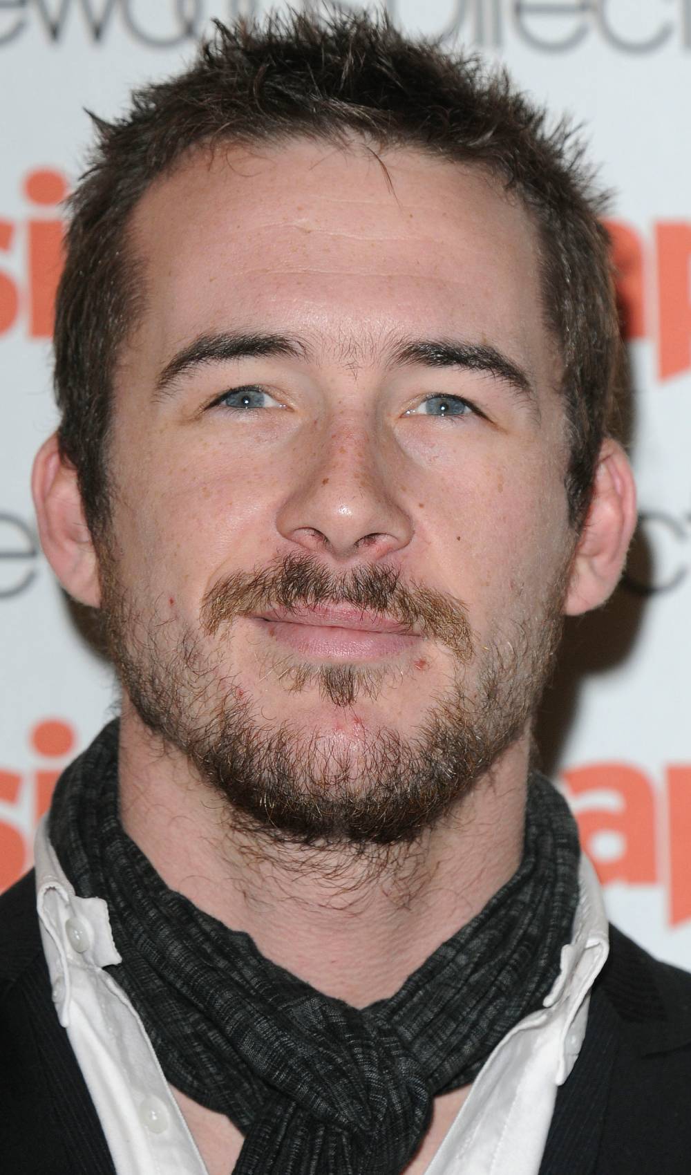 Barry Sloane smiling wearing a scarf