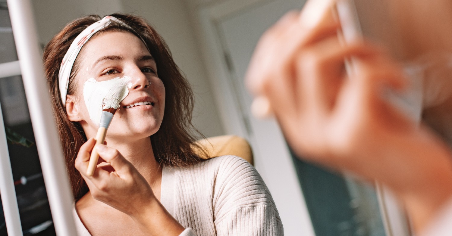 Woman puts on face mask in the mirror