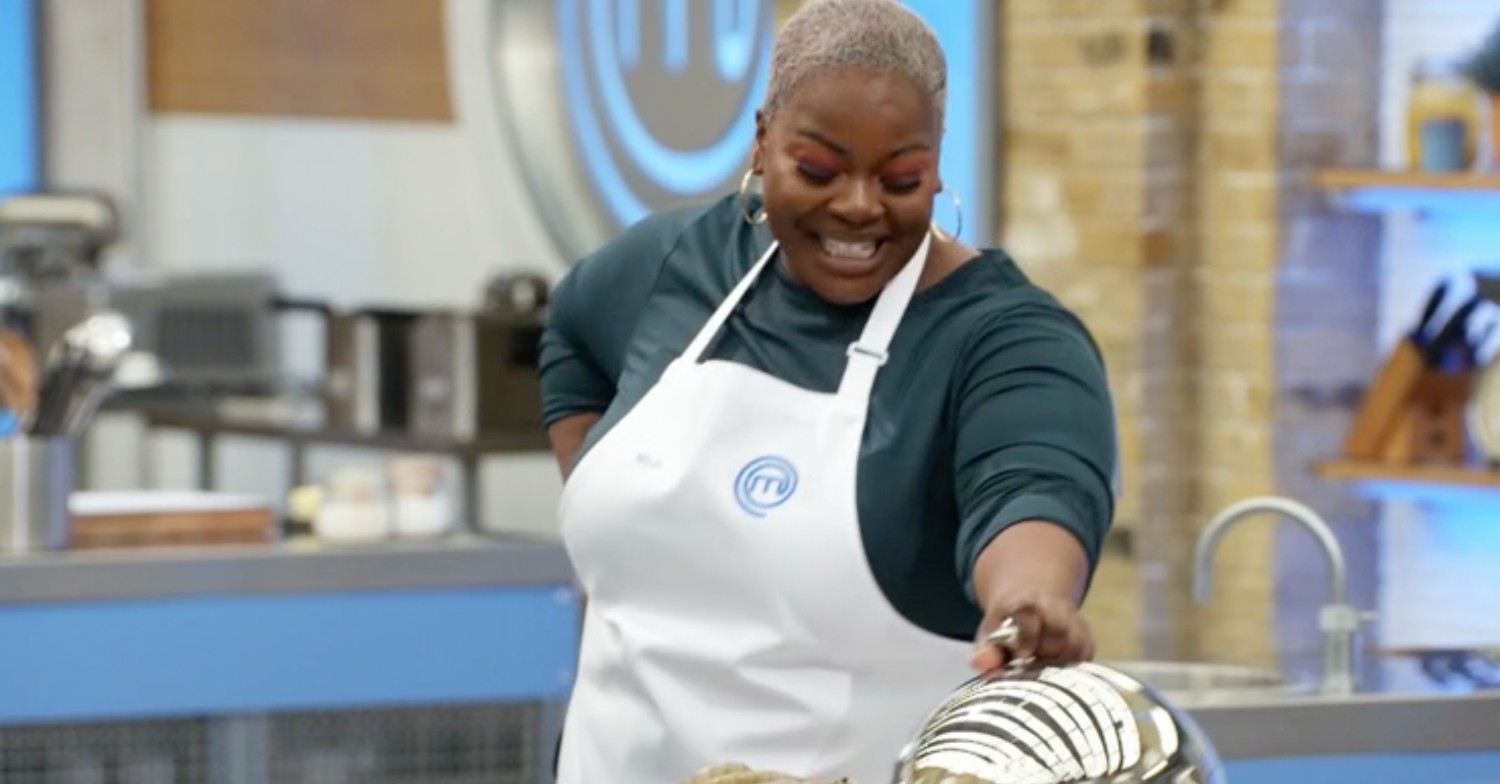 Mojo in the Celebrity Masterchef kitchen wearing a white apron whilst cooking