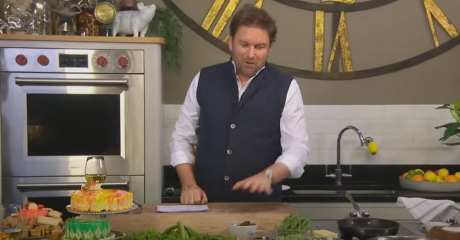 James Martin behind counter wearing a dark waistcoat and looking down