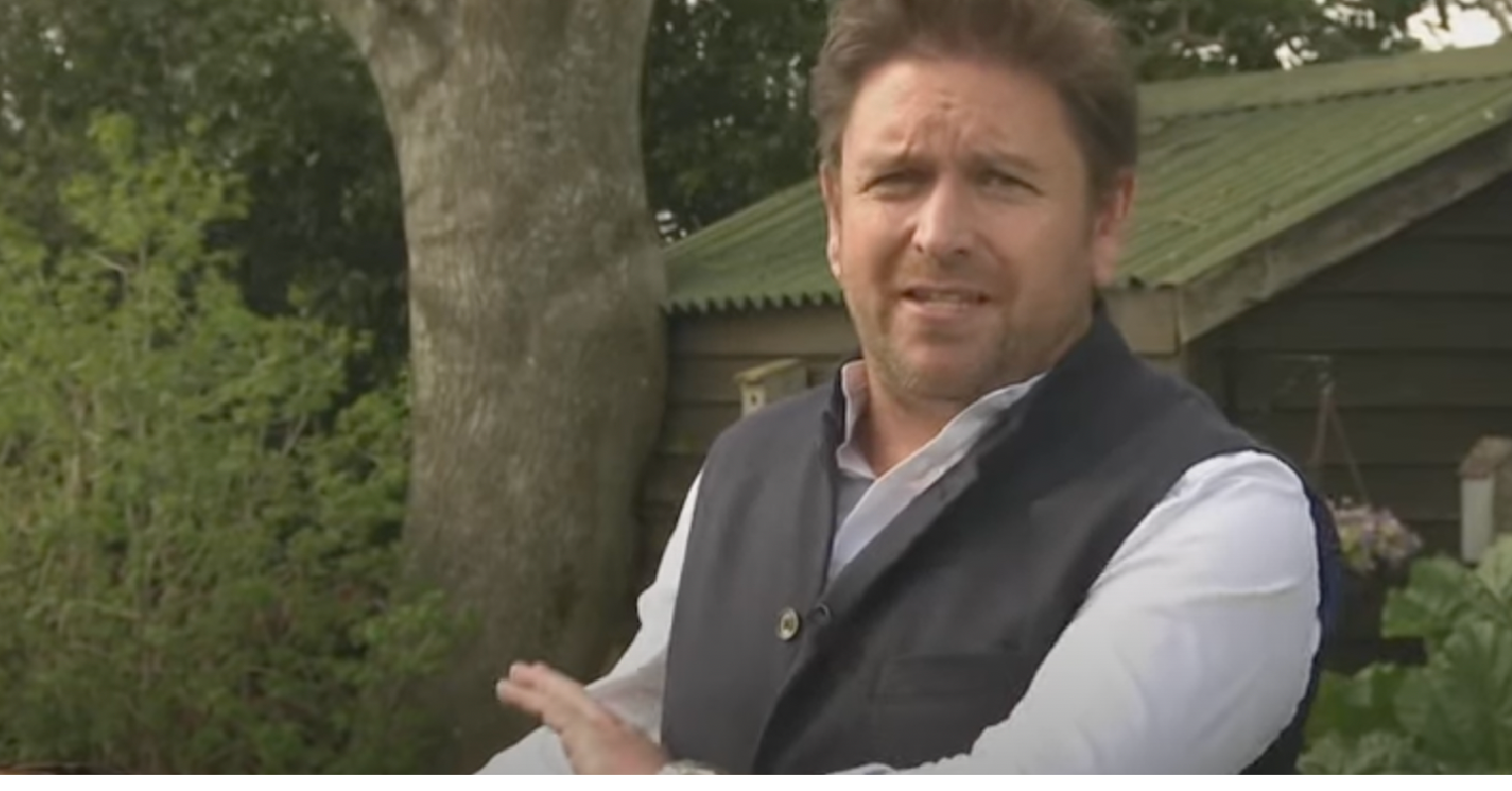 James Martin presenting outside looking to camera while wearing a dark waistcoat