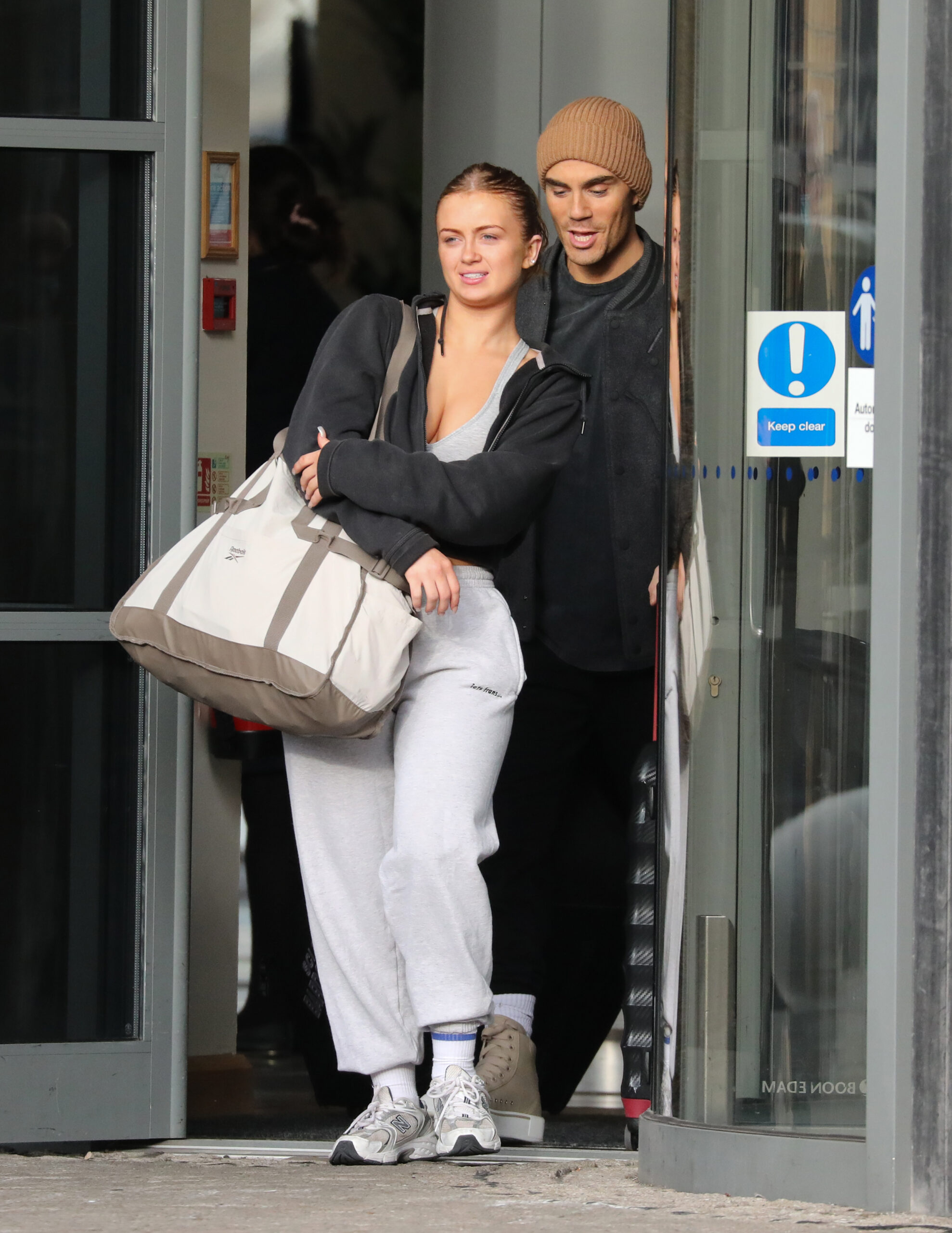 Maisie Smith and Max George leaving a hotel holding bags. 