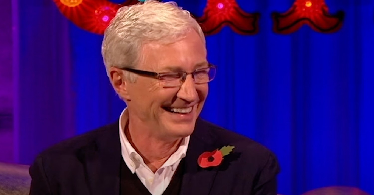 Radio 2 star Paul O'Grady wearing a suit and poppy while laughing