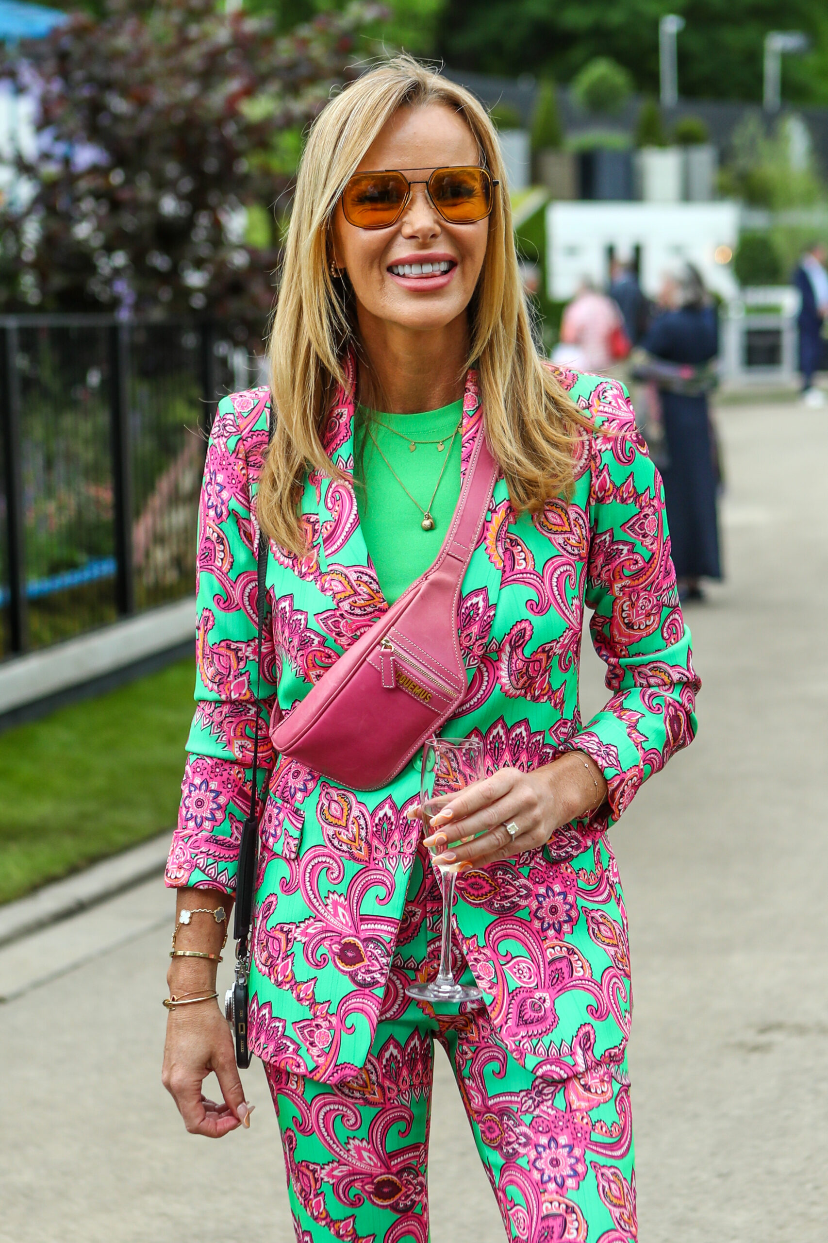 Amanda Holden wearing sunglasses and a pink and green patterned suit. 