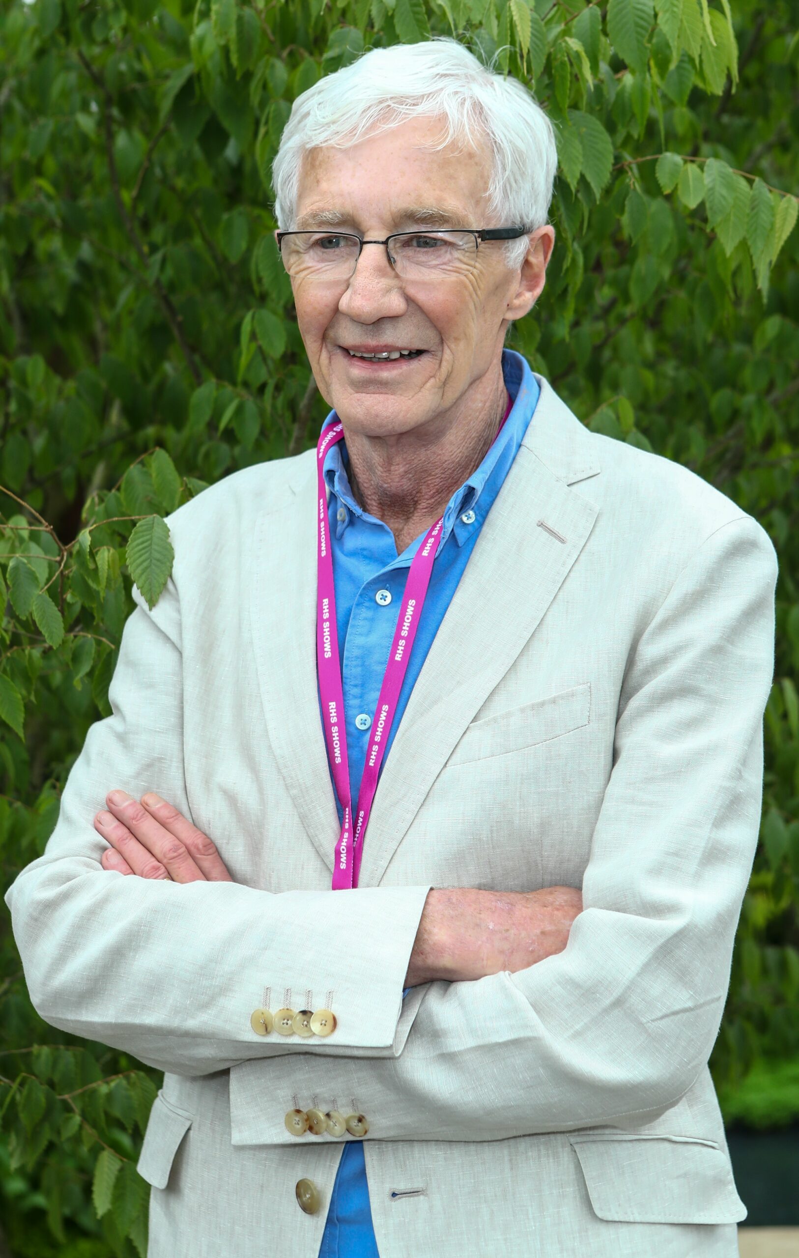Paul O'Grady smiling with his arms folded at Chelsea Flower Show
