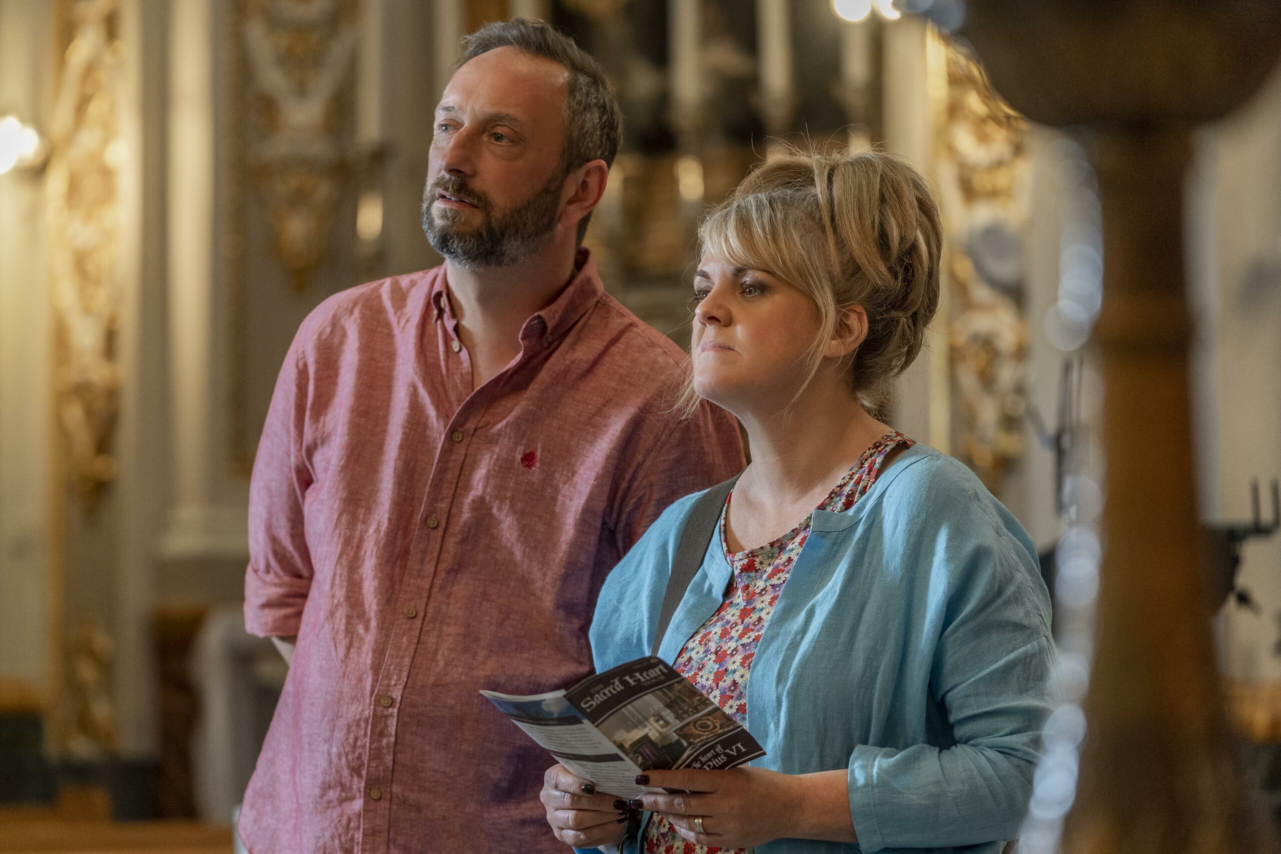 STEVE EDGE (LEFT) AS DOM AND SALLY LINDSEY (RIGHT) AS JEAN IN THE FIFTH EPISODE OF THE MADAME BLANC MYSTERIES, THEY ARE IN A CHURCH