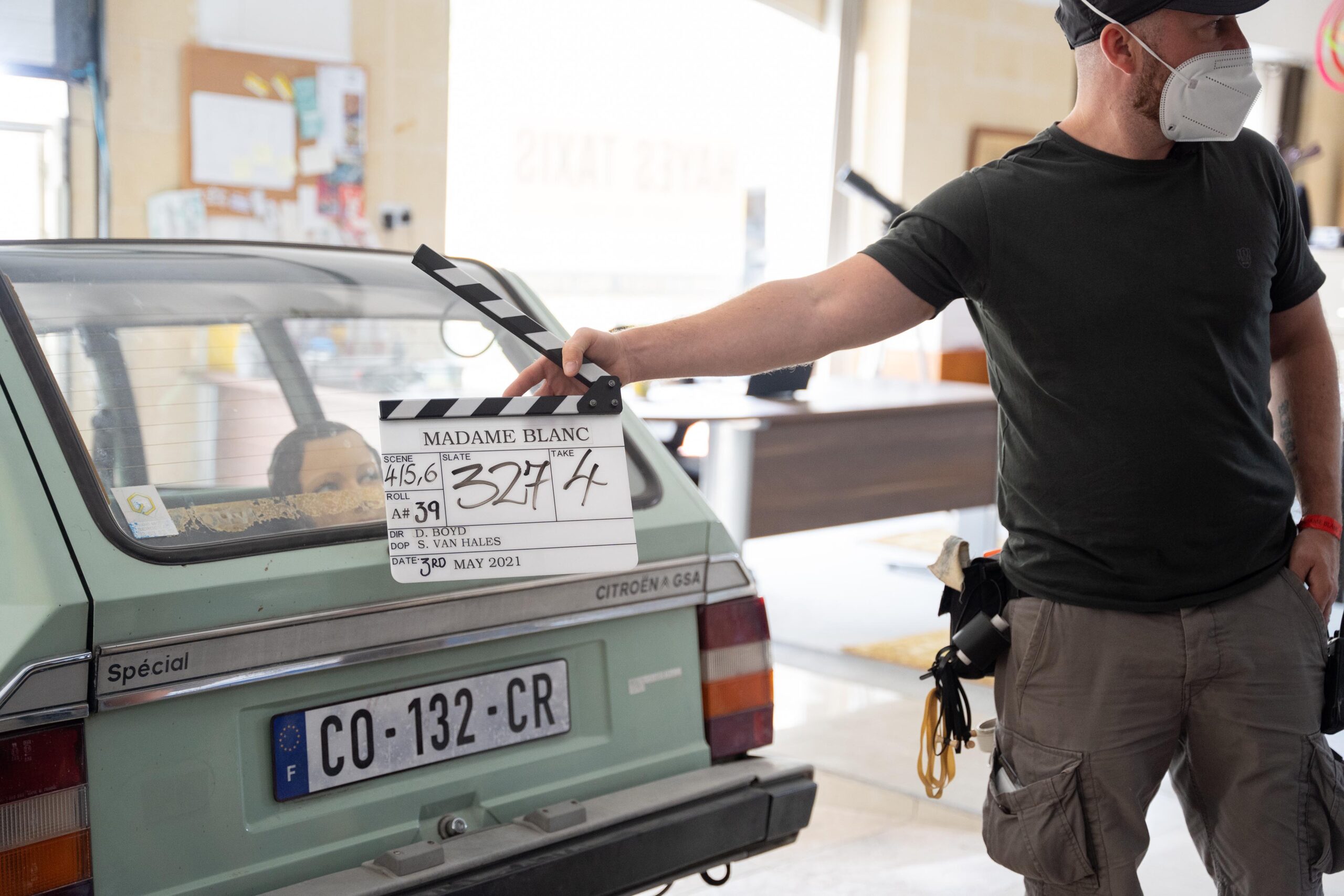 Behind the scenes of The Madame Blanc Mysteries - the image shows a french car with a clapperboard in front of it