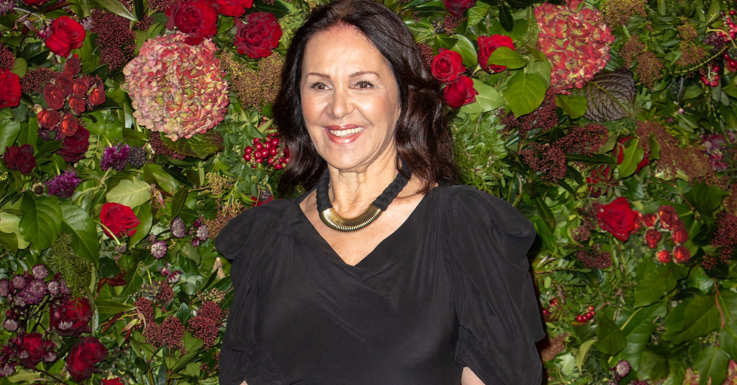 Dame Arlene Phillips smiling with flowers behind her
