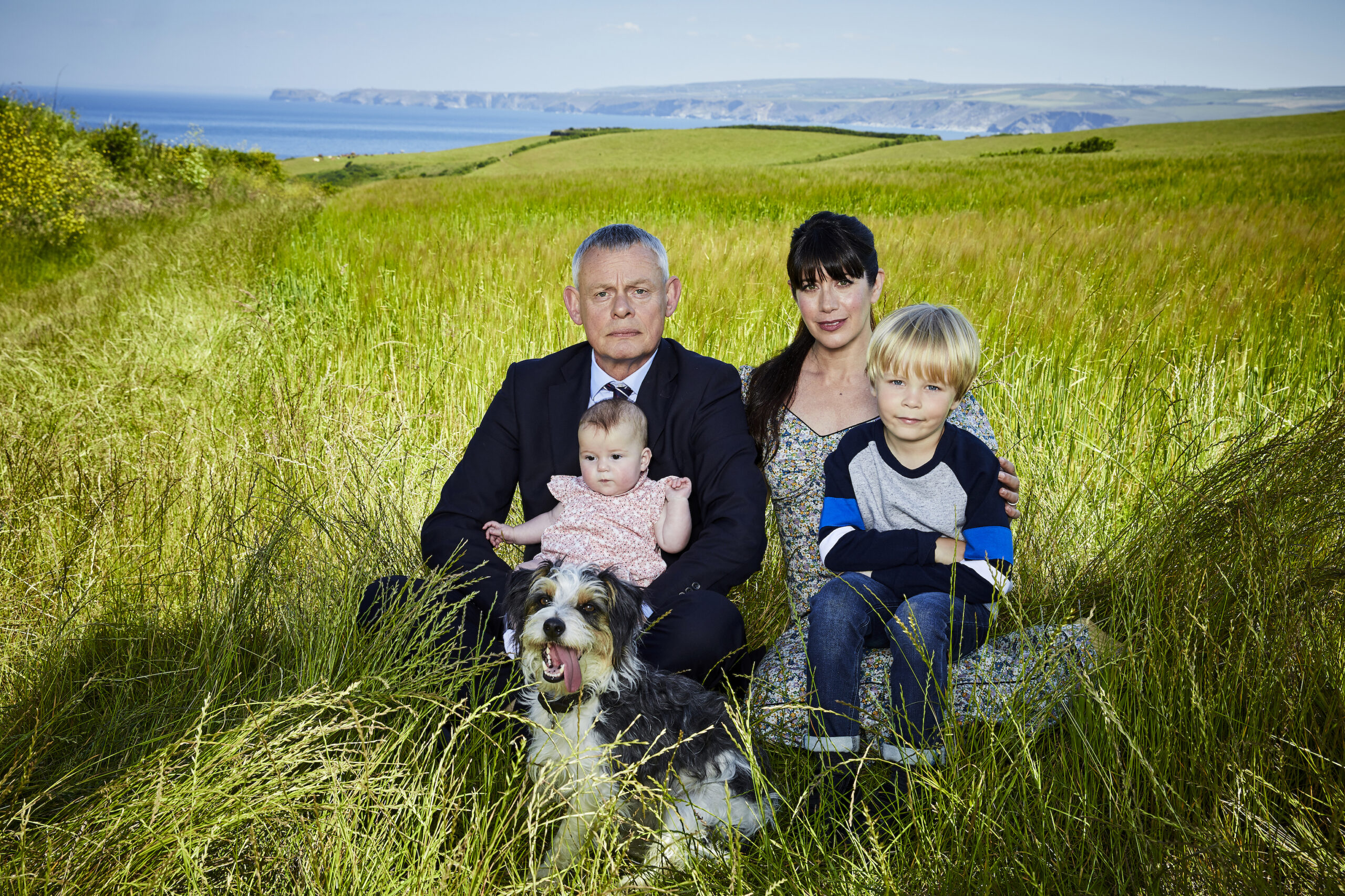 Doc Martin promo shot - family sat in the grass looking grumpy