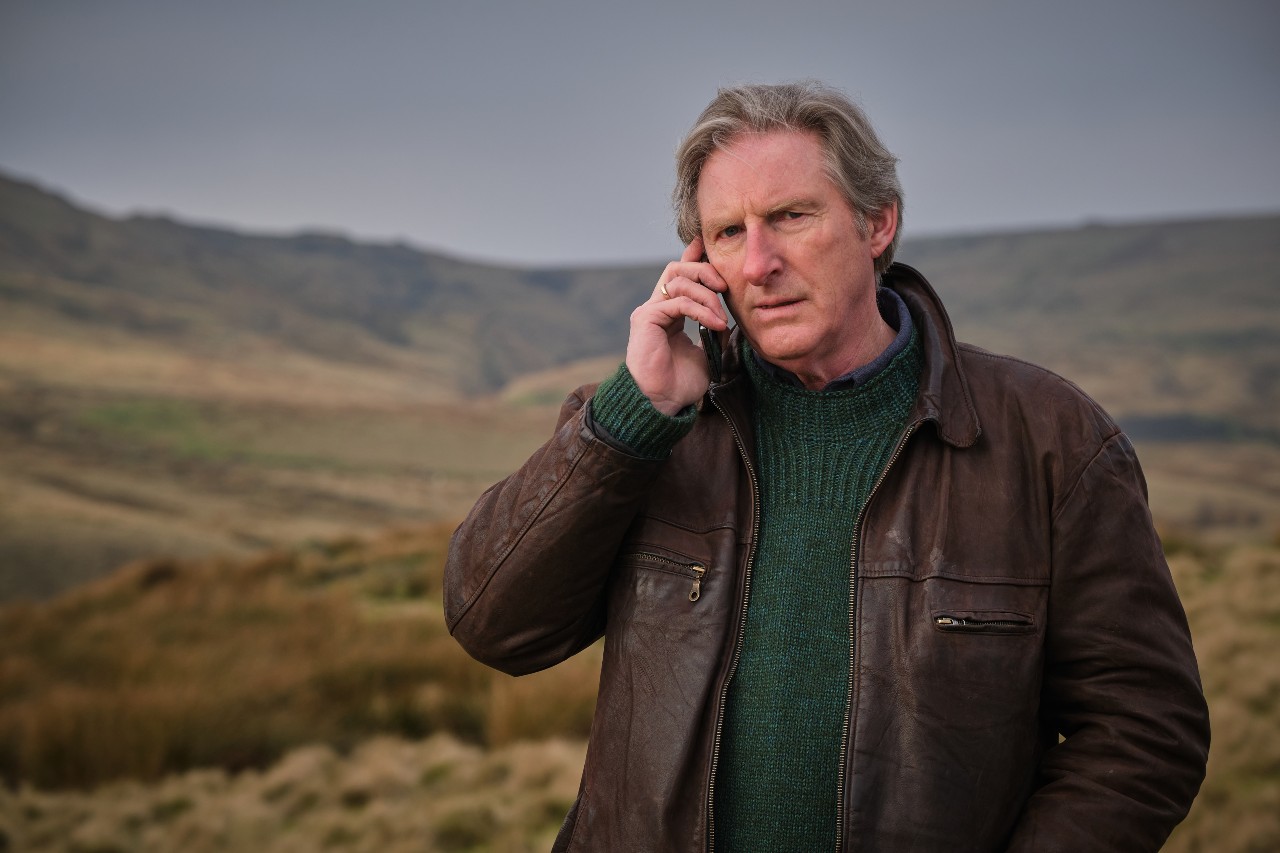 AdrIan Dunbar as Ridley, he stands on the Moors on the phone