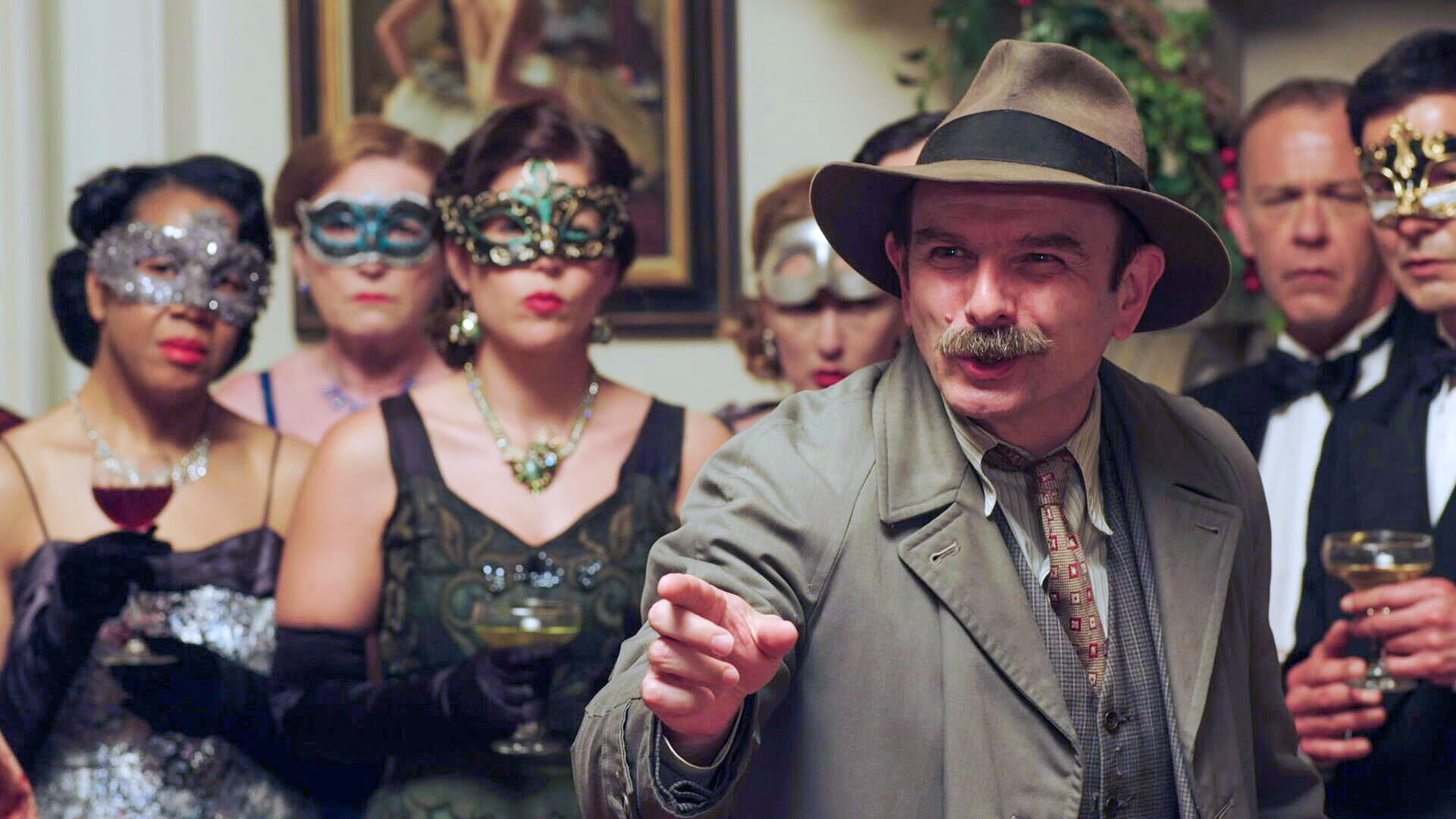 Jack Deam as Inspector Mallory in Father Brown, he stands in a crowd at a party in a detective outfit with a proud look on his face