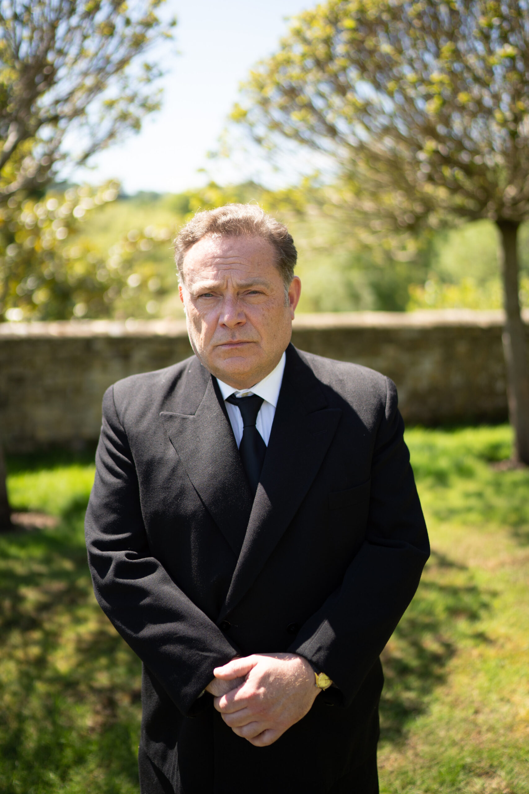 John Thomson looking morose in black in episode of Father Brown