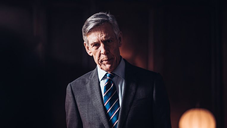 Douglas Reith as The Dean in Professor T, he looks angrily into the camera in a Cambridge college