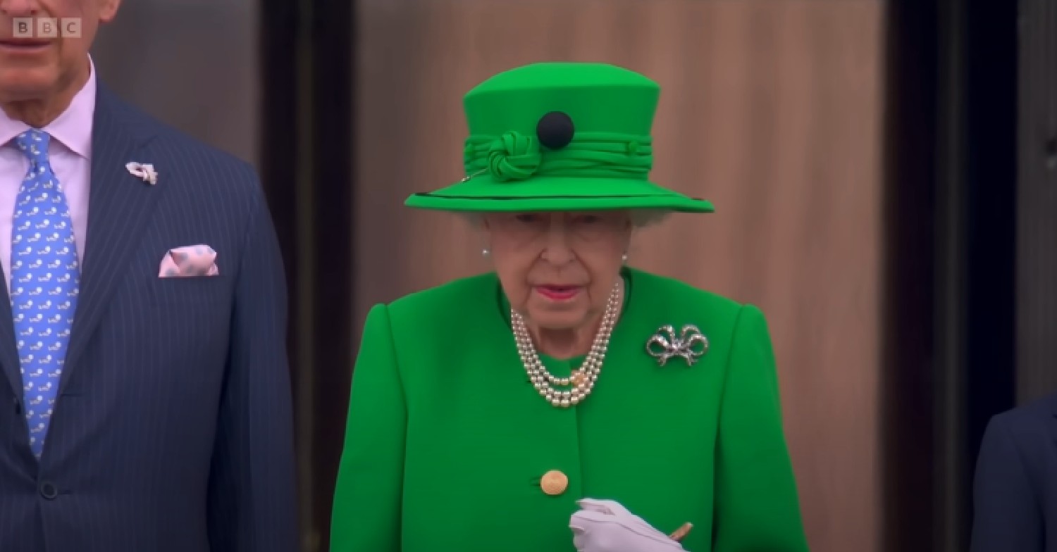 The Queen looks serious in all green outfit on palace balcony