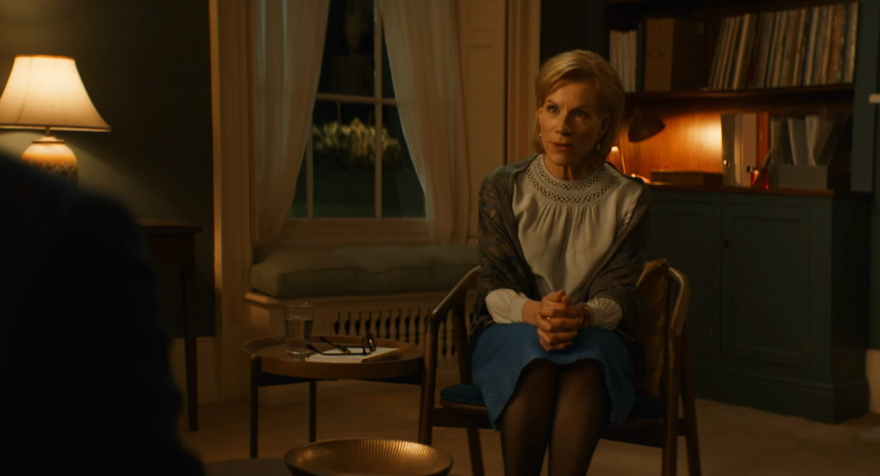 Juliet Stevenson as Dr Helena, she sits in her office with her hands on her knees, looking determined