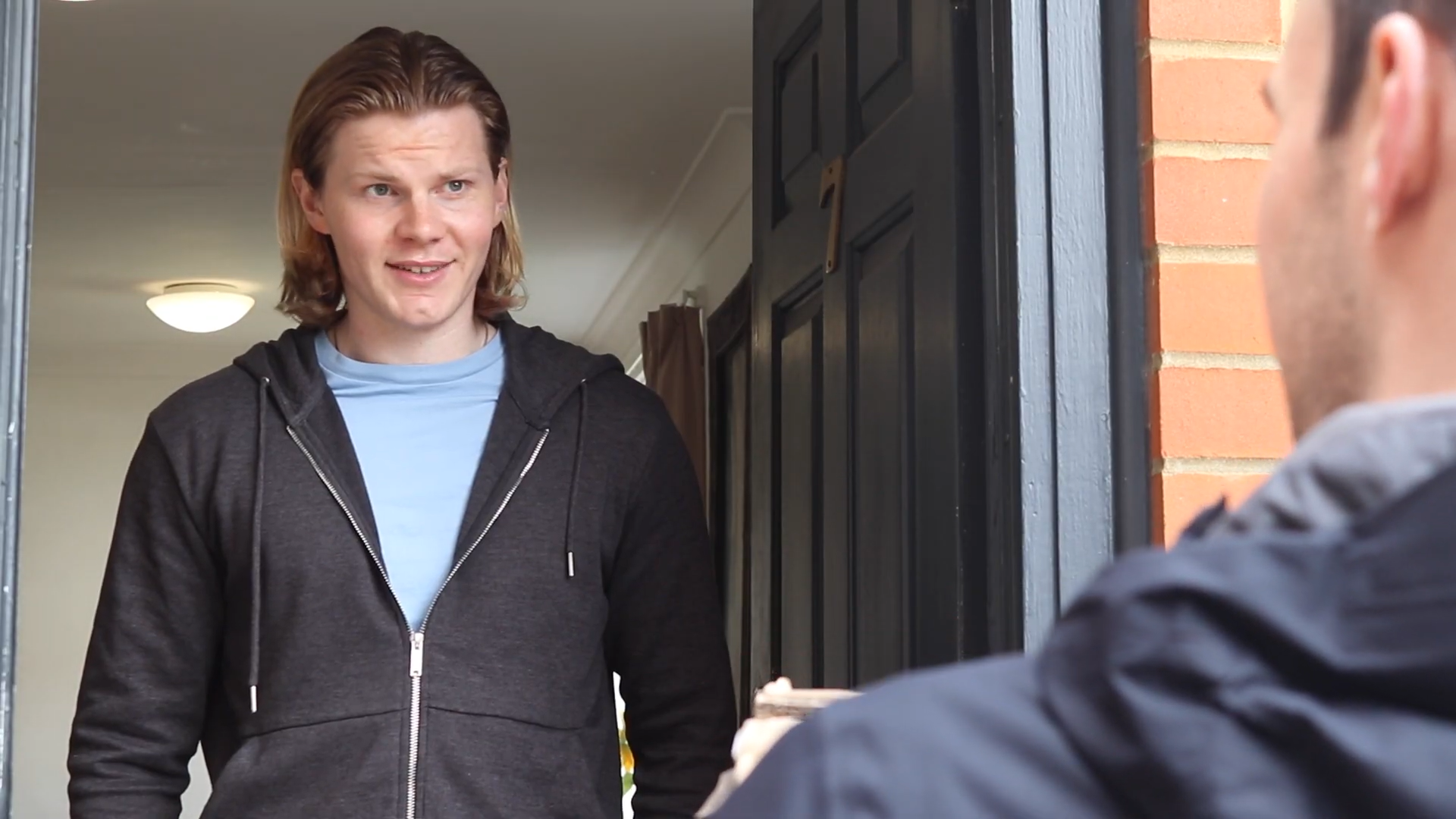 Jack Hesketh in Youtube short Living Together, he stands in a open doorframe looking down at his friend