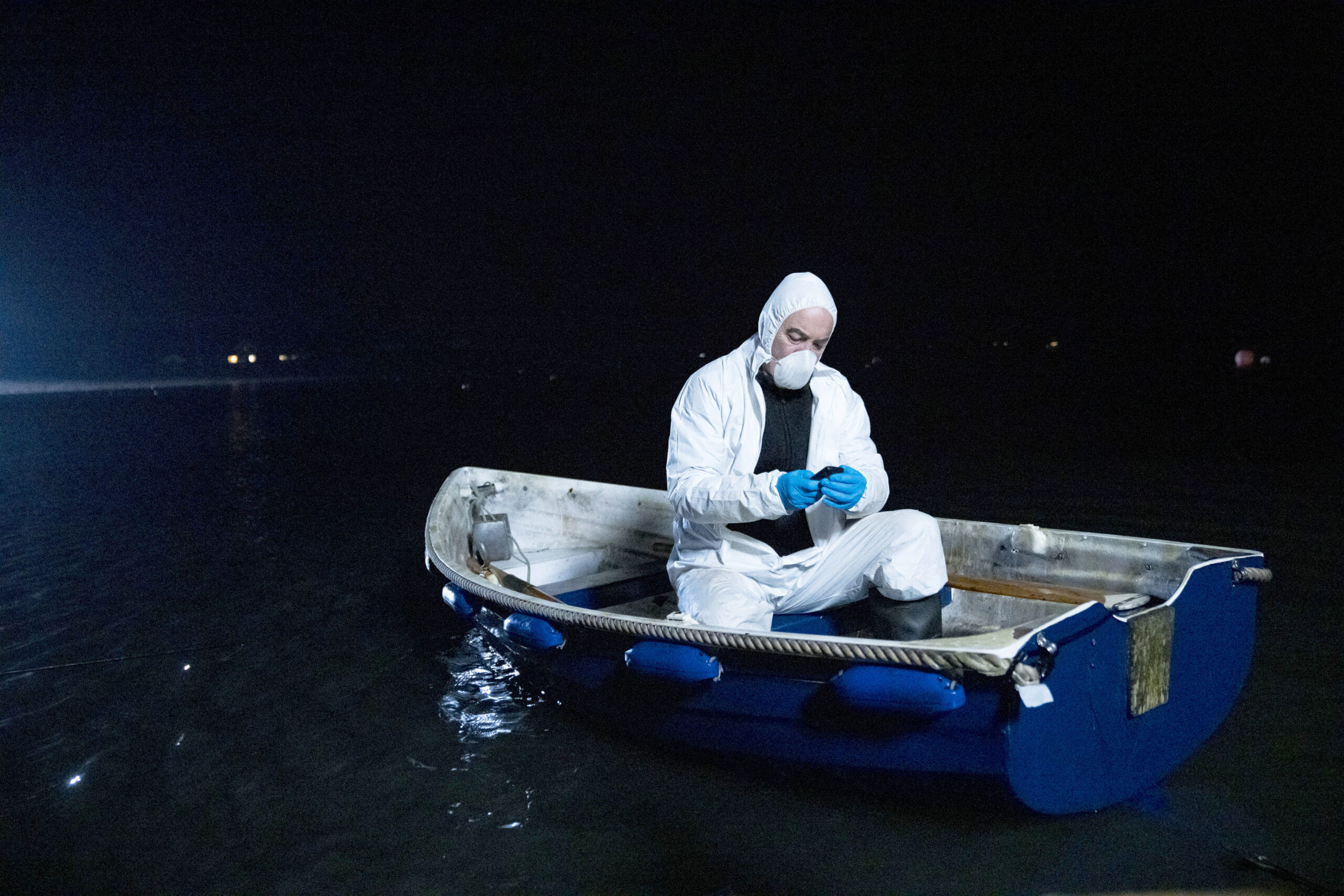 James Nesbitt as Tom Brannick, he is in investigation clothing, in a boat on the water